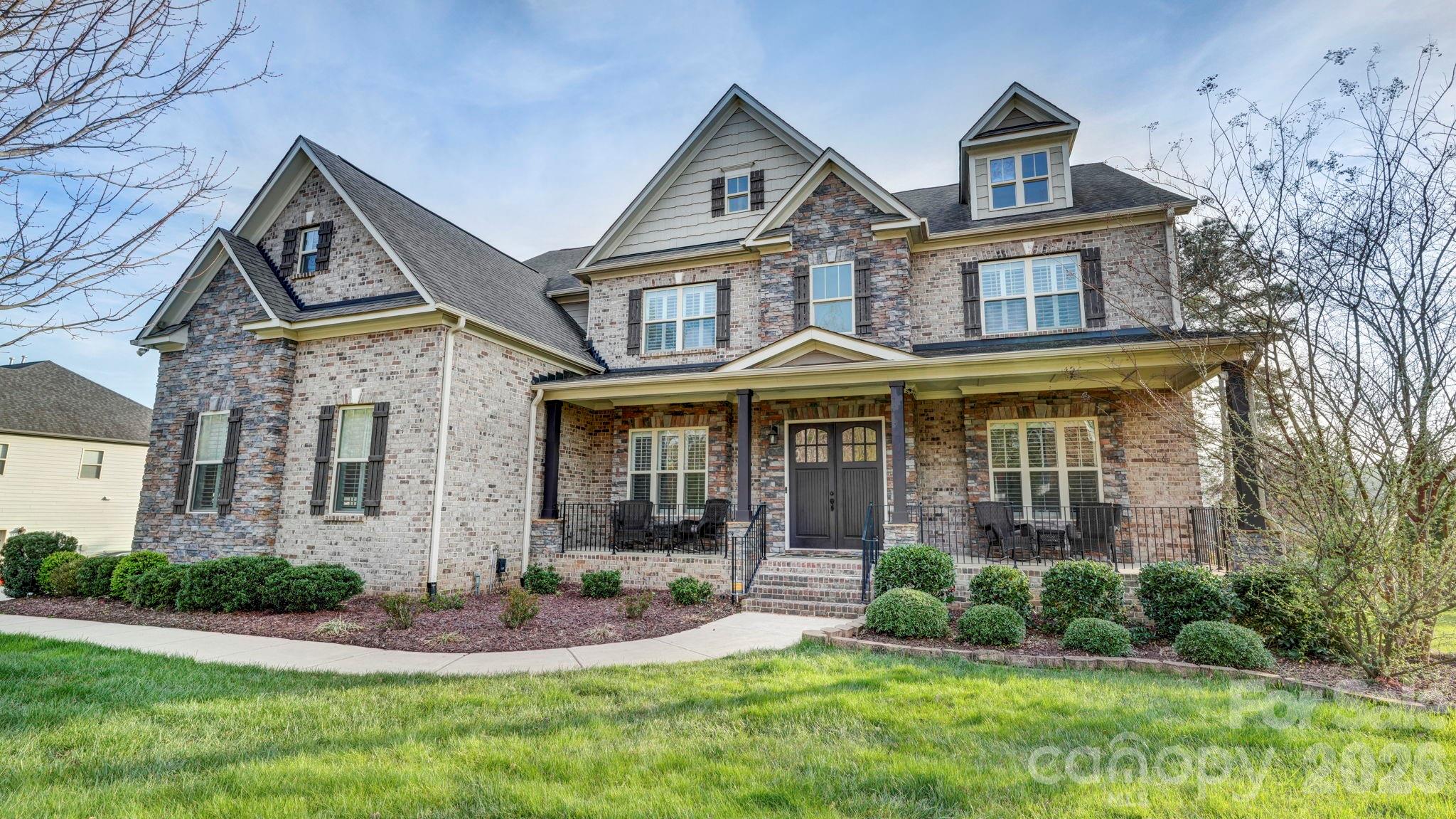 SO MUCH HOUSE FOR THE MONEY! Plenty of space, heavily upgraded, and prime corner lot. This all brick/stone 2-story with basement welcomes you with a rocking chair front porch, and double doors to a striking two-story foyer. It opens to the study/office, and the formal dining room with butler's pantry. The 2-story great room is dramatic with built-ins, a stone fireplace, and a wall of windows. It connects to the breakfast area, and the kitchen with white cabinetry, gas cooktop, double ovens, and a spacious island. From there, you'll find what could be a second pantry, used most recently as a second home office. The drop zone leads to the 3-car garage with epoxy floors. There's also a main floor guest suite. Upstairs, there are 4 more bedrooms, and 3 full baths including the expansive primary suite with sitting area and fireplace. The bath has dual vanities, tub and separate shower, and not one, but two walk-in closets, one the size of a bedroom. The full daylight basement offers even more opportunities, with flex areas for gaming/gym, a bar with sink/fridge and microwave, and a home theater. Plantation shutters throughout the house, even in the basement, and incredible storage areas with custom shelving. Relax on the covered back porch with composite decking, or on the lower paver patios, including one with a fire pit and fountain. Amenity filled community offers a clubhouse, pool and splash pad for the kids and is assigned to award-winning Clover Schools. Welcome home!