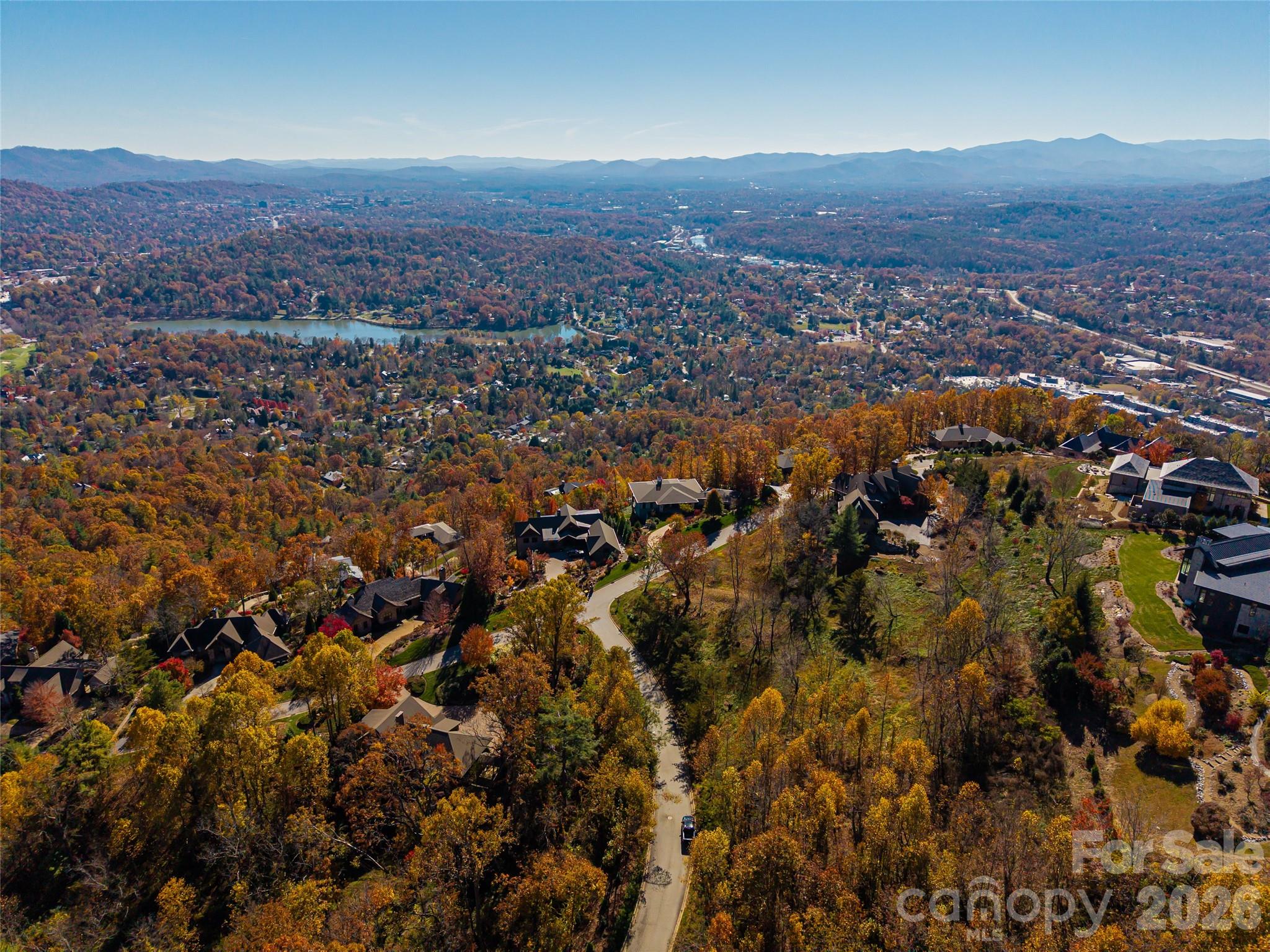 Perched gracefully above the city lights, this exceptional homesite in Reynolds Mountain captures some of Asheville’s most breathtaking vistas — one of the last remaining lots to offer a true panoramic view of downtown Asheville, The Grove Park Inn, Beaver Lake, and the rolling northeastern Blue Ridge Mountains beyond.

With approximately 180 degrees of sweeping, unobstructed views, this lot invites the design of a residence that fully embraces both sunrise and sunset. The natural topography is ideal — gently sloping to accommodate an elegant main-level entry with a walk-out lower level, creating seamless transitions between indoor comfort and outdoor living. The driveway is already cut in, winding through a serene landscape to a perfectly positioned, level build site — ready for your vision of a modern mountain retreat or timeless estate.

Set within the prestigious and established community of Reynolds Mountain, residents enjoy a refined yet vibrant lifestyle. Gather with neighbors at the community’s picnic pavilion, explore the network of scenic hiking trails, or take part in one of the many social clubs, hobby circles, and volunteer initiatives that make this enclave so uniquely connected.

Conveniently located near the Country Club of Asheville, UNC-Asheville, and the charming boutiques and dining of Reynolds Village, this location offers the perfect blend of tranquility and accessibility — just minutes from the heart of downtown Asheville.

A rare opportunity awaits. With its commanding views, ideal build site, and access to an active and welcoming community, this property stands among the premier offerings in Reynolds Mountain.