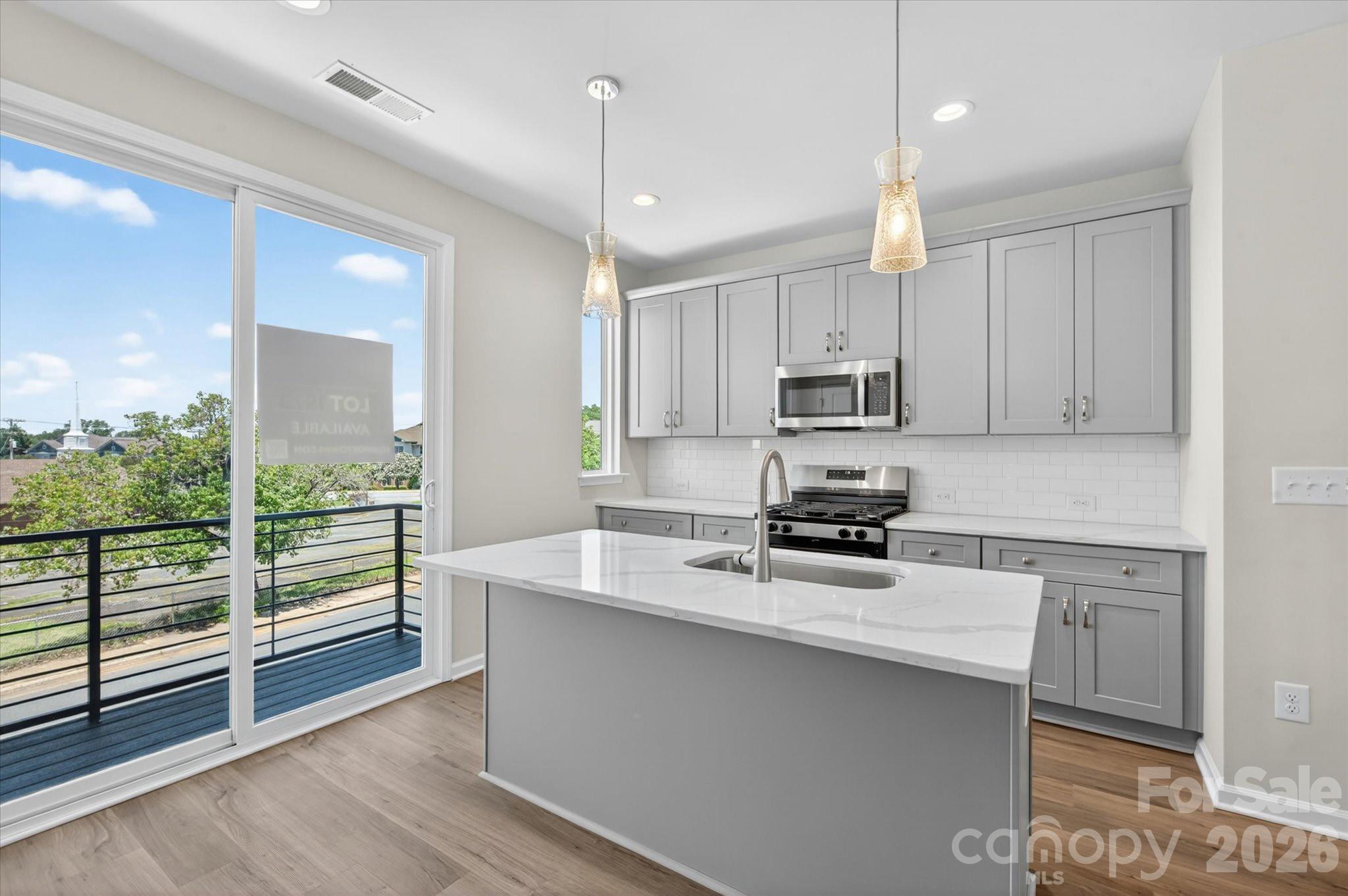 This end-unit townhome has a 1-car garage, 1st floor flex room with powder, 4th floor bedroom with powder, & a spacious rooftop terrace with a slight view of uptown. It's walking distance to Camp North End. Great open layout on the 2nd floor. Kitchen has 42" cabinets w/ brushed nickel hardware, quartz counters, trash pullout, GE SS app w/ gas range. 3rd floor hosts the laundry closet and both bedrooms. Premier bath includes quartz counters, tiled floor, & tiled shower with semi-frameless surround and built-in shampoo niche. Guest bath has quartz counters and tiled floor. Chrome hardware in baths. LVP floors throughout 1st & 2nd floors & 3rd floor landing, with oak treads on all stairs. Walking distance to bars, restaurants, events, and more! Additional street parking is available.