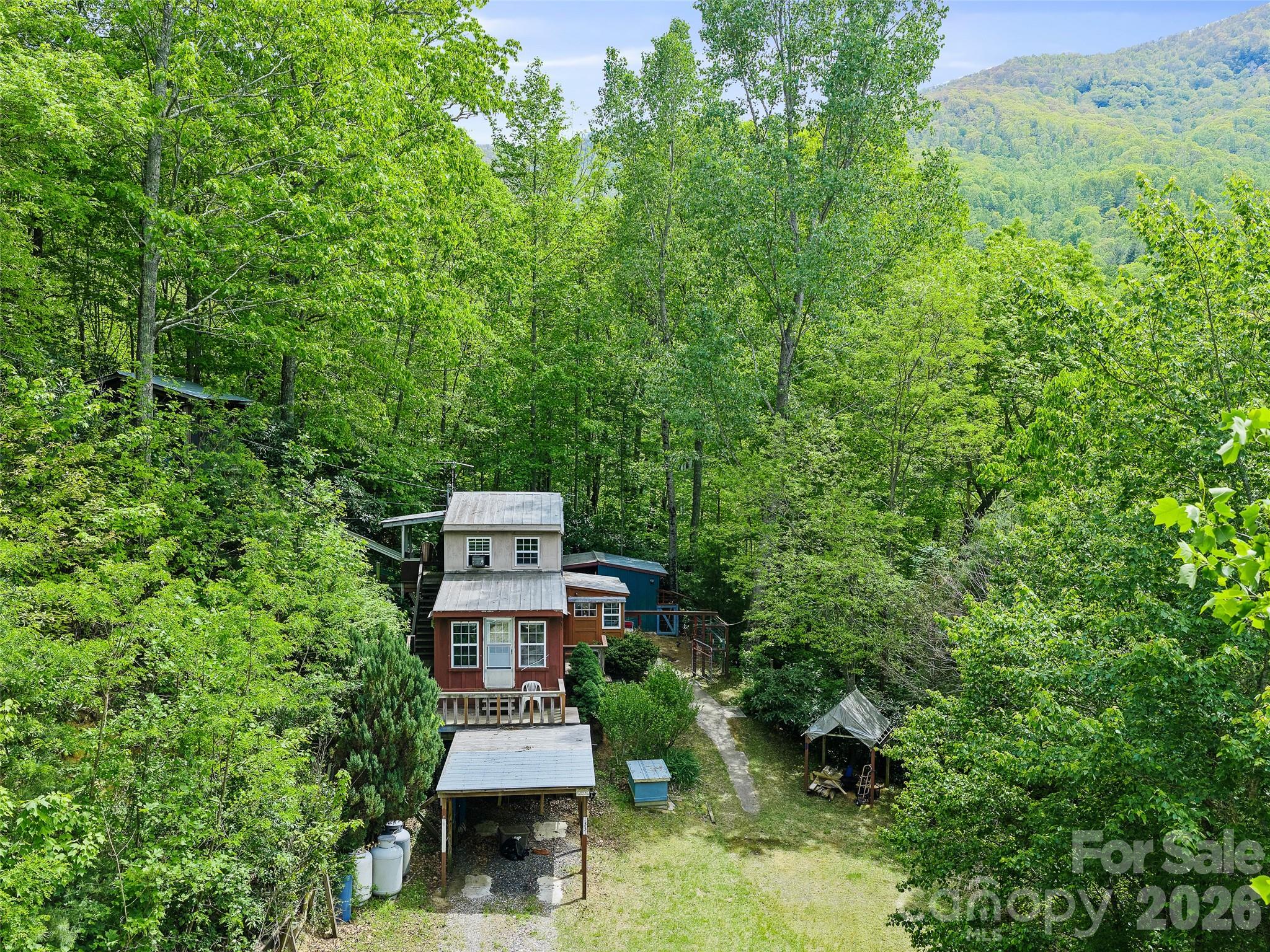 This home is not going to be for everyone, but it is a true original—a custom-built retreat born from the owner’s personal vision rather than a blueprint. While it captures the soul and solitude of a classic cabin, its design breaks away from tradition with unique lines and an unconventional layout. Just enough rooms for living comfortably, the home has a spacious kitchen, half bath and living room on the main level and heated by a freestanding propane fireplace. Up the ship's ladder to the second level is the bedroom and full bath. The mud/laundry room at the back entrance off from the kitchen is convenient and helps keep the outdoor dirt and grime from entering the home. The property features a large detached screened entertaining porch in the back and a front porch for private time coffee sipping. Built with self-sufficiency in mind, the home has its own greenhouse and a cellar/canning house in the back. There is plenty of storage with a shed and a workshop space as well. Do you need a fenced-in area for Fido? We have got you covered. If you are looking for privacy and convenience to town, 1331 Georges Fork checks those boxes.