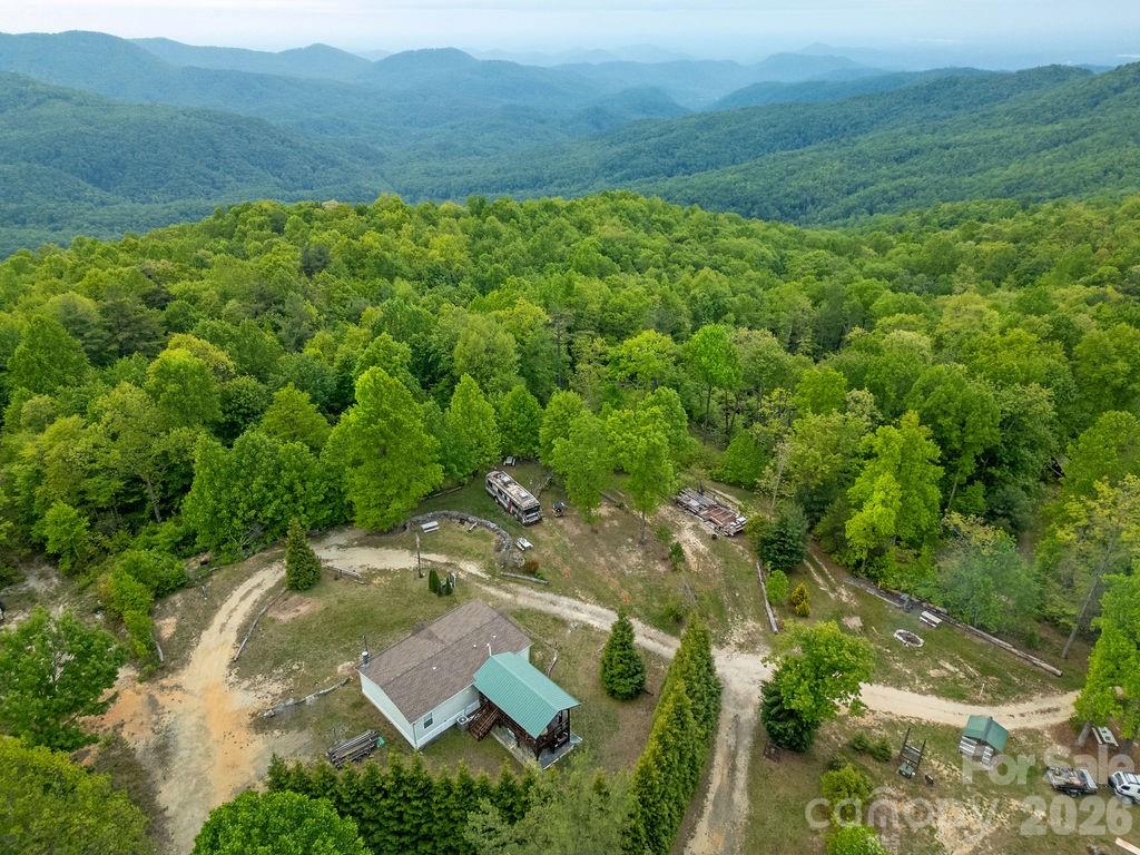Here’s your chance to own a stunning mountain property that also serves as a truly unique income-producing opportunity. Named “Camp Seven” by the current owner, this is a rare and special find offering privacy, views, and established infrastructure already in place. Set on 13.3 acres, the property features a fully developed private campground with seven full hook-up campsites, each equipped with water, electric, and septic. Whether you’re looking to operate a boutique campground, expand an outdoor retreat business, or simply enjoy a private mountain escape with income potential, this property delivers exceptional versatility. The setting is nothing short of remarkable, with long-range views overlooking Upstate South Carolina, Lake Keowee, and Lake Jocassee. A private logging road provides access throughout much of the property, revealing a landscape rich with mature hardwoods, natural springs, rock outcroppings, and panoramic mountain scenery. The main residence is a well-maintained, one-level home designed for comfortable mountain living, featuring a welcoming rocking chair front porch, and a large covered back porch perfectly positioned to take in the expansive views. It has an single-level layout for convenience and accessibility. Additional improvements include a workshop and a small corral, supporting both recreational and operational use of the property. There are also a few primitive tent sites already in place, with ample room for additional expansion or future development.
Properties that combine livable residential comfort with established income-producing infrastructure are extremely rare—especially in a setting this private and scenic. Whether used as a full-time residence, vacation retreat, or turnkey campground operation, “Camp Seven” is a must-see opportunity.