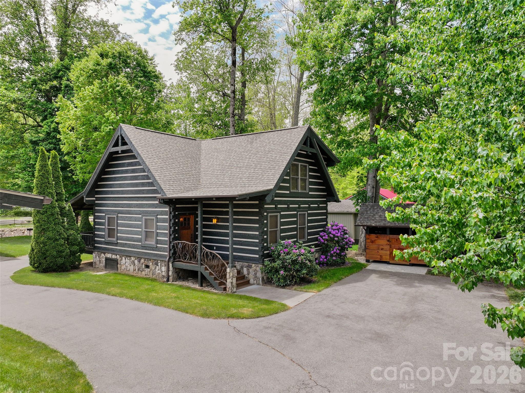 Gorgeous, unique, and rare find is this creek front log cabin w/2BD/2BA being sold completely furnished & fully equipped. This charming retreat is perfectly situated close to trout-rich Soco Creek. Relax on your covered back porch & watch family enjoying fishing & tubing in the creek. This meticulously maintained cabin features a vaulted great room w/a floor-to-ceiling stone fireplace &hardwood flooring. The kitchen boasts granite countertops, rustic-style cabinetry, & a spacious dining area. The main floor includes a king-size primary suite w/a granite-topped vanity & a ceramic-tile tub/shower. A stunning staircase w/rhododendron pickets leads to the upper level which offers a loft w/a pull-out couch & an additional guest suite. Relish the tranquility of a community w/just 9 other cabins where the HOA handles mowing & landscaping for you. In addition to the creek you'll appreciate the scenic twin rock waterfalls. Maggie Valley Golf & Resort is only minutes away for your convenience. STR's Allowed!