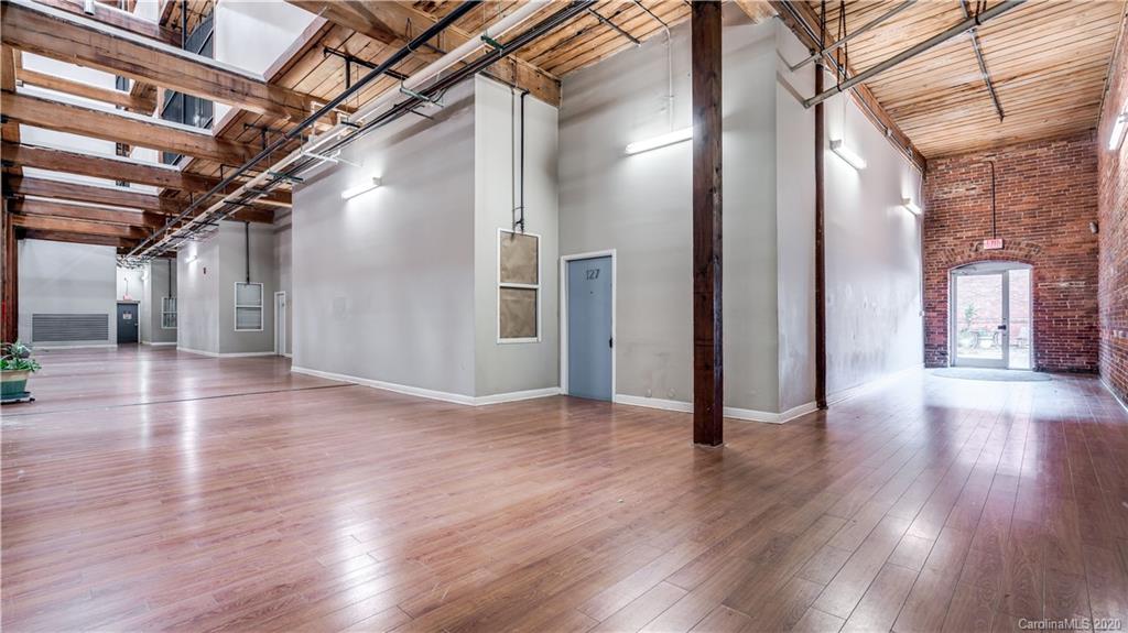 Don't miss this great opportunity to live in a historic converted cotton mill with easy access to uptown. This 2 bedroom, one bath main floor condo is conveniently located to the parking lot. Features include 17' high ceilings and 12' high arched windows which fill the space with sunshine! Two story brick walls, exposed duct work, wood ceilings and new flooring. Other recent upgrades include: concrete kitchen counter tops, recessed lighting, bathroom and kitchen tile, fresh paint, new stair railing and water heater. One of the few units with its own laundry hook up.
