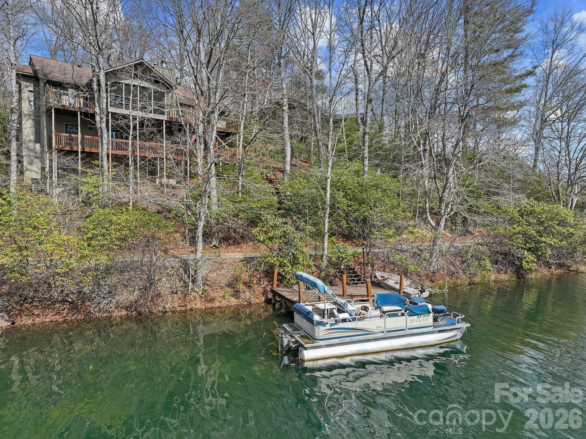 Enjoy lakefront living at its best on one of the most beautiful, clean lakes in Western North Carolina. This updated home has a split floorplan with vaulted ceilings on the main level and great views of Lake Ticoa throughout. 2 Bedrooms and full bathrooms are full of light on the main level with laundry and high end kitchen. Primary suite is a great size with sitting area, large bathroom with tub and tiled shower. Enjoy the outdoors in the vaulted screened porch with premium lake views of that super clear water. The lower level has 3 bedrooms and a full bathroom with a large den / family room. The lower level is a walk out basement with easy access to the back yard and your private dock. There are two unfinished rooms that are great for storing all your lake toys as well. 2 car detached garage on main level gives you plenty of room to park and exit the sloped driveway. All open decking is in need of replacement and is reflected in the price. Both boats to convey. All this located within the gated community of Connestee Falls with social clubs, hiking trails, clubhouse, new wellness center, restaurants, golf, pickleball and much more! One time fee of $14,000 paid at closing to CFPOA. Call listing agent with any questions.