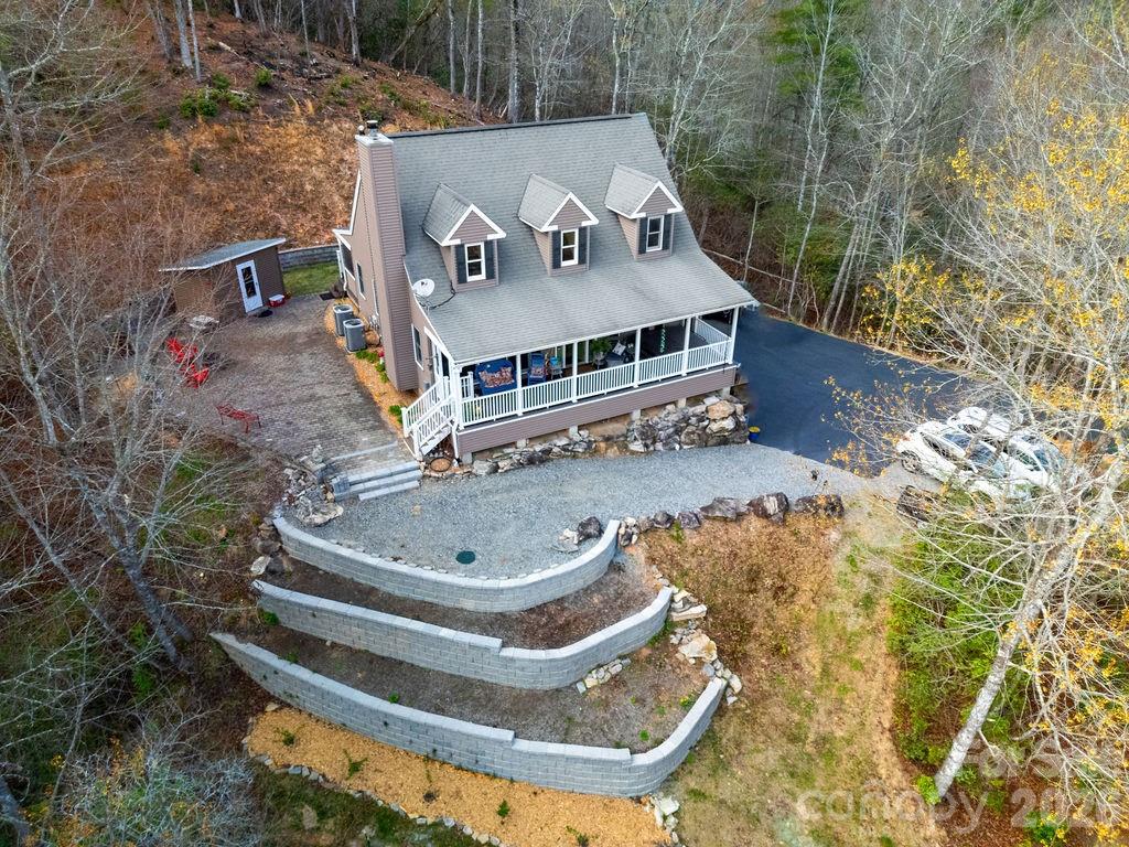 Perched at the end of the road high on a mountainside, this stately home offers unmatched privacy on 18 breathtaking acres. Surrounded by nature, the property is a true retreat with exceptional outdoor living. Relax in the jacuzzi, unwind on the rocking chair front porch or screened back porch, and gather around the stone fire pit while taking in tranquil mountain sunrises and sunsets. Explore terraced gardens, hike scenic trails, or ride an ATV along the path that winds throughout the entire property.
Originally built by a contractor as his forever home, this residence was constructed with quality and durability in mind—truly overbuilt to stand the test of time. Inside, the impressive living room welcomes you with soaring ceilings, custom built-ins, a cozy wood stove, and abundant natural light from skylights above. The dining area flows seamlessly from the living space and connects to a beautifully appointed kitchen featuring custom slate tile countertops, cherry cabinetry, a breakfast bar, and stainless steel KitchenAid appliances. A convenient laundry room/pantry is located just off the kitchen. The main level also includes a half bath and a spacious primary suite with a luxurious bath, double vanity, and extensive tile work. Upstairs, you’ll find two additional bedrooms, a full bath, and a versatile office space—all with stunning views from nearly every room. The finished basement offers a bonus room and a half bath, along with an oversized two-car garage and ample storage. Additional features include wiring for a generator, with a portable generator included. At the base of the paved driveway, a private 24x36 detached garage provides even more flexibility, it could be used as a potential second living quarters—perfect for guests, rental income, or multi-generational living. All of these features and privacy and you are only 4.6 miles from Main Street Brevard and all of it's shopping and dining. This home is truly a "must see"!
