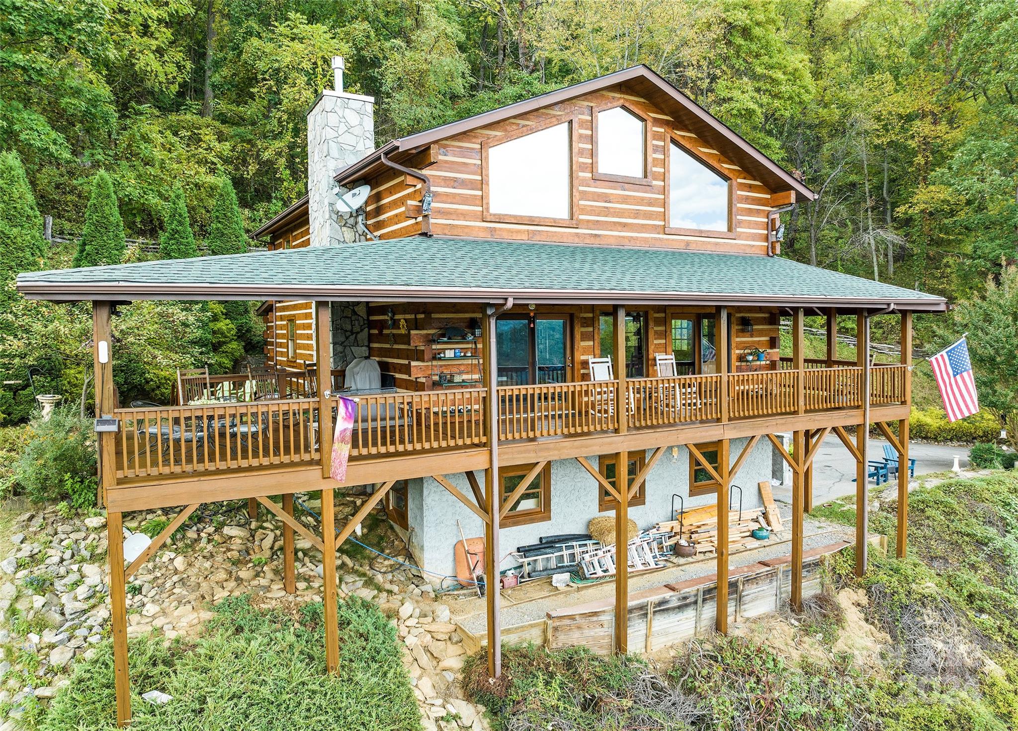 Amazing views from this true log home overlooking Maggie Valley with 180-degree views from one end of the Valley to the other! Stepping onto the wrap-around porch, there's plenty of room for your rocking chair or grilling and entertaining. Inside, you are greeted by the 2-story great room, hardwood floors, exposed beams, and natural light from the many south-facing windows.  Great room includes a stone-faced gas log fireplace, open floor plan with the dining and kitchen areas (granite counters, gas stove). The primary bedroom with ensuite, guest 1/2 bath, and a spacious pantry/laundry complete the main level. Upstairs: a bedroom, full bath, and open loft for your spare bed or office. The 2-car garage, storage room, and large workshop are in the basement. Driveways to the basement and main level carport. 2024 stained, 2023 roof, Generator, 2019 heat pump. Tankless water heater. Spectrum fiber internet/TV, Vacation rental allowed. $25,000 for the additional lot above. City Sewer & Trash.