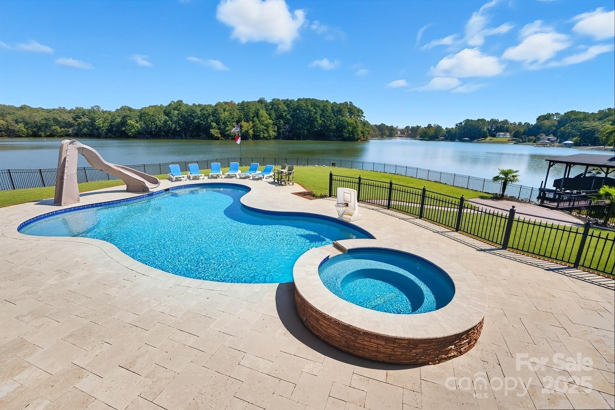 Welcome to Your Lake Wylie Paradise in Beautiful Belmont! Live the lakefront lifestyle you’ve always dreamed of in this stunning, full-brick custom home, perfectly positioned on a level point lot with panoramic lake views and protected conservancy land in the background.  Designed to embrace the outdoors and capture breathtaking water views from nearly every room, this property features a massive covered porch, swimming pool with hot tub, and lush, professional landscaping. Whether you're entertaining guests or unwinding with family, this space is ideal. Water lovers will appreciate the private boat ramp, spacious covered dock with boat lift, and two jet ski lifts—ready for endless lake adventures. From the moment you enter the grand foyer with its sweeping staircase, you’re greeted by gorgeous hardwood floors, rich crown molding, and thoughtfully designed living spaces. The formal dining room offers the perfect setting for both elegant dinners and casual gatherings. The Great Room boasts soaring ceilings, a cozy gas fireplace, custom built-ins, and large windows that flood the space with natural light and stunning lake views. The gourmet kitchen features stainless steel appliances, double ovens, granite countertops, a center island, and a sunny breakfast area. Just off the kitchen, the fabulous sunroom invites you to linger with your morning coffee, read a book, or simply soak in the tranquil lake views. It would also make a perfect home office. Relax in the main-level primary suite, complete with tray ceiling, serene lake views, and a spa-like bath with premium finishes. Upstairs, you’ll find two additional bedrooms, two full baths, a spacious bonus room, and a flex room perfect as an office, 4th bedroom, or playroom. Abundant storage throughout ensures everything has its place. There is even a large workshop/storage area in the crawl space.  This beauty features a brand new high-efficiency geothermal heat pump for HVAC, along with an electric water heater supplemented by geothermal auxiliary heating. Fully fenced backyard and in-ground irrigation. Recently renovated primary bathroom, fresh paint, and new carpet.  Nestled in the charming town of Belmont, enjoy the best of both worlds—peaceful, small-town living with convenient access to Uptown Charlotte, the airport, and major shopping destinations, just a short drive away.