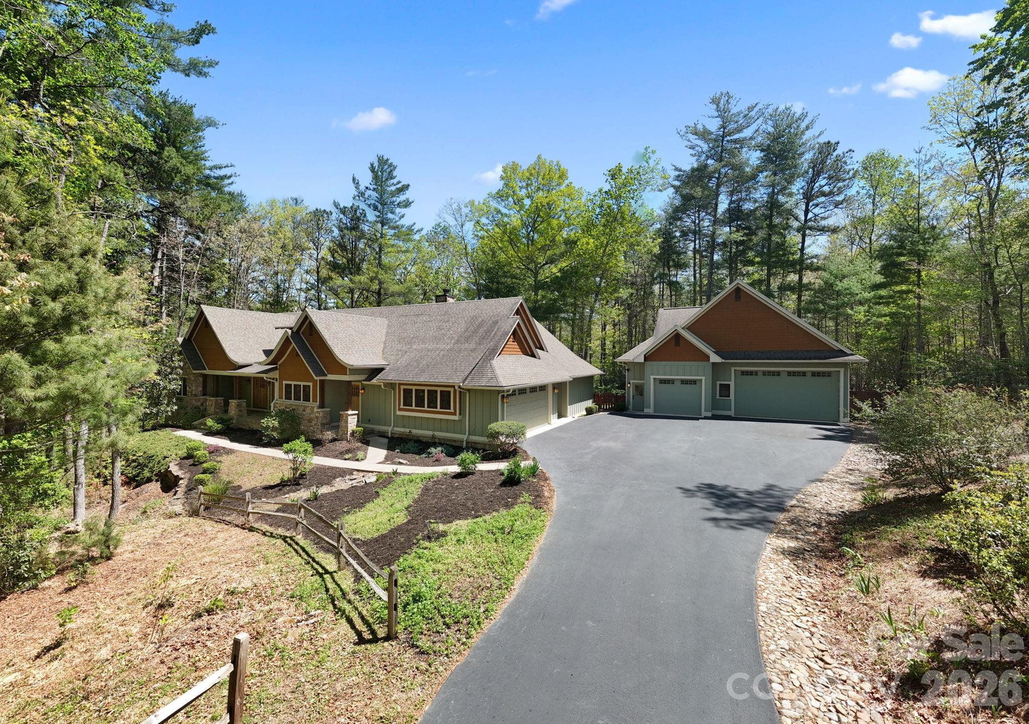 Framed by a canopy of mature trees and artfully naturalized grounds, this bespoke Arts & Crafts residence set on 3.1 acres offers just under 3,400 square feet, with 4 bedrooms, 4 full baths, and 2 half baths - thoughtfully scaled for entertaining and effortless living in Fletcher’s desirable Cane Creek valley, conveniently located between Asheville and Hendersonville. From the moment you arrive along the tree-lined approach beside Taylor Ranch, where dappled sunlight filters through the canopy and longhorn steer graze against soft mountain vistas, the setting unfolds slowly and deliberately, offering a daily reminder that you are somewhere distinctly different.

A welcoming stone porch opens to a gracious foyer and central living space, intentionally designed for both intimate moments and elevated entertaining. The kitchen is a true showpiece, anchored by an oversized island and appointed with solid wood cabinetry, a walk-in pantry, and a six-burner gas range with griddle and heat-lamp hood. It flows seamlessly into the family room, where custom built-ins, a striking stone wood-burning fireplace, and a well-appointed wet bar create an inviting atmosphere. Casual and formal dining spaces offer versatility, while a refined FLEX ROOM provides the perfect setting for a private office, library, or den.

Wake to serene wooded views in the main-level primary suite, complete with a gas fireplace, dual dressing rooms, and a spa-inspired bath designed for true relaxation. A separate wing offers two additional spacious bedrooms and bathrooms, while upstairs, a second primary suite with sitting area and en suite bath provides exceptional flexibility for multigenerational living, guests, or a private studio.

Thoughtful daily conveniences, including a discreet “friendship entry,” drop zone, a generous laundry room, and a tool shed enhance livability without compromising design. Outdoor spaces are equally compelling: a screened and covered deck immersed in the trees, and a broad stone patio with a recessed four-seat hot tub create a private, resort-like retreat ideal for year-round outdoor living.

The detached oversized three-car garage includes a 10-foot door, epoxy flooring, half bath, mini-split, and unfinished loft/attic, offers endless potential for a studio, workshop, or additional living space. Modern systems, including a whole-home generator, tankless water heater, radon mitigation, moisture control in the crawlspace, and integrated Control4 audio, provide comfort and peace of mind.

Set within the private gated community of Ashbrook, with wooded walking trails, community pavilion, firepit, and equestrian riding ring, this residence offers a rare balance of seclusion and accessibility just minutes from Asheville and Hendersonville’s dining, shopping, breweries, outdoor recreation, healthcare, and the Asheville Regional Airport. Enjoy year-round outdoor living with nearby hiking and mountain biking, along with space to garden and engage with the natural surroundings. Schedule a private tour today.