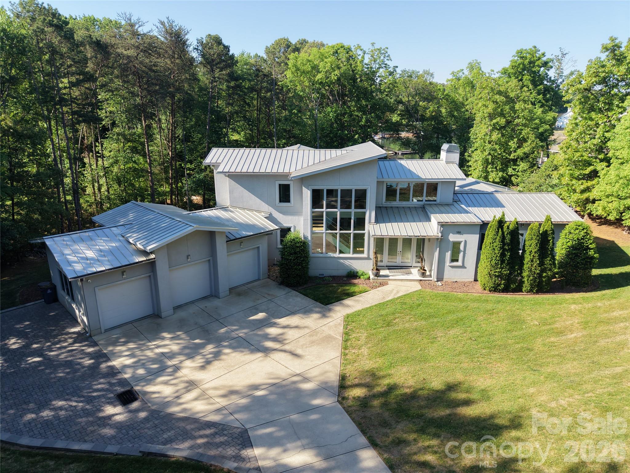 Rare opportunity to own a Simonini-built contemporary waterfront masterpiece in The Point, offering exceptional privacy, modern luxury, and unmatched flexibility with no HOA, CC&Rs, or rental restrictions. Nestled on a sprawling 1.4-acre lot, this architecturally striking home was enhanced with interior design by one of the country’s top designers and blends sophistication with comfortable lakefront living. Membership to The Point Golf Club is available, adding access to one of Lake Norman’s premier lifestyle communities.

Designed for seamless indoor-outdoor living, soaring floor-to-ceiling windows capture stunning lake views while expansive sliding glass doors open to a covered lanai featuring ceiling heaters and an automated screen system for year-round enjoyment. The private dock with lift makes lake days effortless, while the resort-style pool with spillover spa and travertine decking creates an incredible outdoor retreat.

Inside, the chef’s kitchen is equipped with premium Thermador appliances including a 42" built-in refrigerator, 48" cooktop, double ovens, warming lights, custom Blum cabinetry, and a beautifully designed drop zone with inset cabinetry. High-end finishes continue throughout with custom wood stairs and cable railing, sea grass wallpaper accents, Visual Comfort designer lighting, auto shades, and fresh paint throughout.

The luxurious primary suite offers a spa-inspired bath with heated floors, digital shower controls, an EAGO jetted soaking tub, and a large laundry room conveniently located within the primary closet, plus an additional upstairs laundry closet. Smart-home features include Sonos whole-house audio, Honeywell automation for HVAC, humidifier, lighting, and security, two commercial-grade 50-gallon water heaters with recirculation, whole-house water filtration, buried propane tank with WiFi monitoring, standing seam steel roof, and garage with epoxy flooring and new openers.

For auto enthusiasts or those needing additional space, the lot offers room to build a detached garage to the left of the home. A rare combination of privacy, design, waterfront lifestyle, and modern convenience in one of Lake Norman’s most desirable locations.