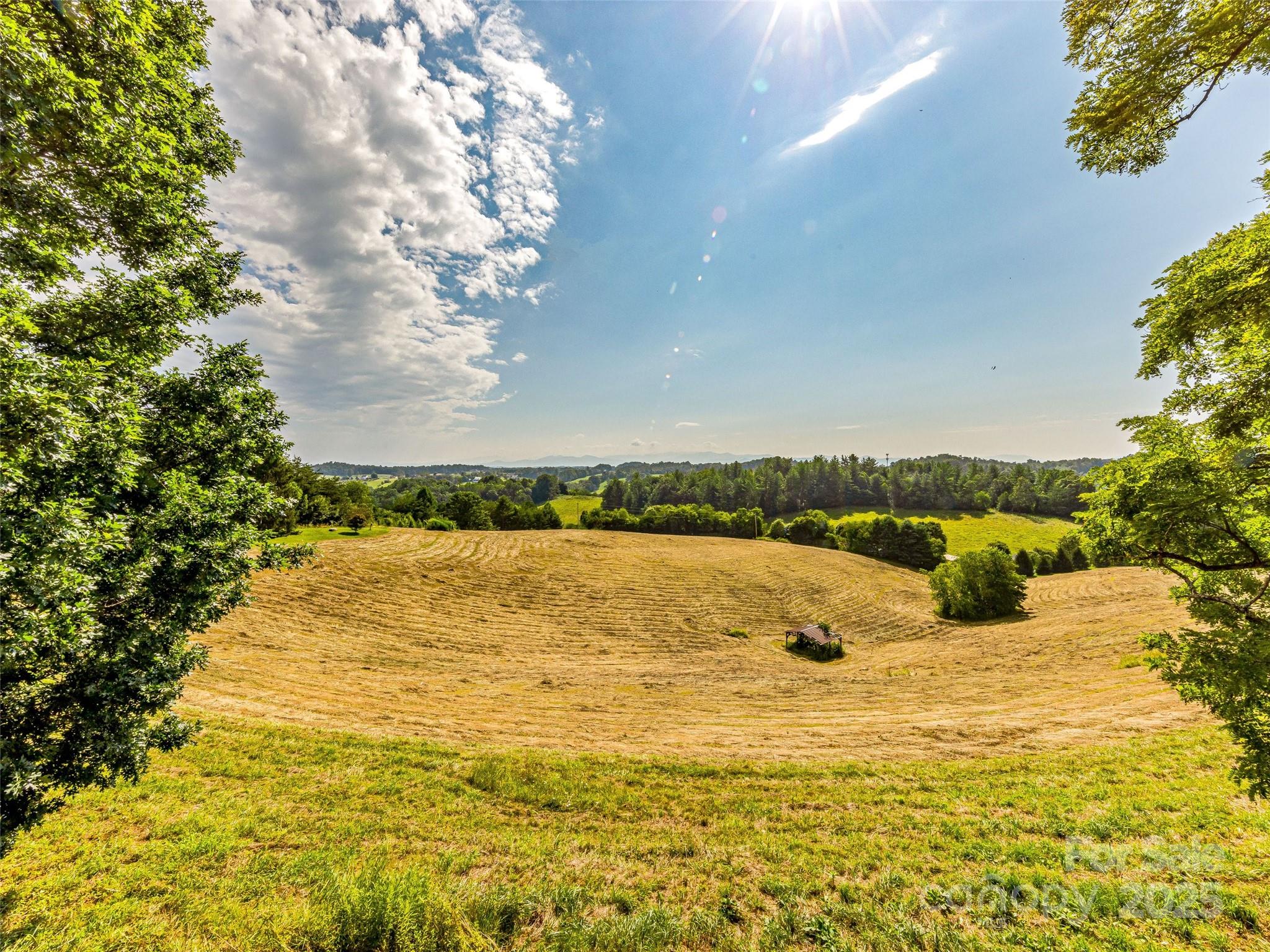 Be inspired by this cherished family estate set on 64.5 acres of rolling land, offering panoramic sunrise long range mountain views over lush pastures. Owned by the same family since the '80s, this remarkable property has served as a treasured mountain family retreat. It features three meticulously crafted homes with expansive living and entertaining spaces, including a heated pool, tennis court, large barn with outbuildings, a charming mini chapel, and beautiful shade trees amidst acres of landscaped grounds. The spacious, architecturally designed brick main home blends open living areas with stunning gardens and mature landscaping. The large working barn offers ample storage with additional outbuildings. Come and walk over a mile of trails with multiple view areas. All with an easy paved, gated access only 20 minutes from Asheville. This rare private estate and family compound offers family retreat, event venue, re-development or farming opportunities. The possibilities are endless!