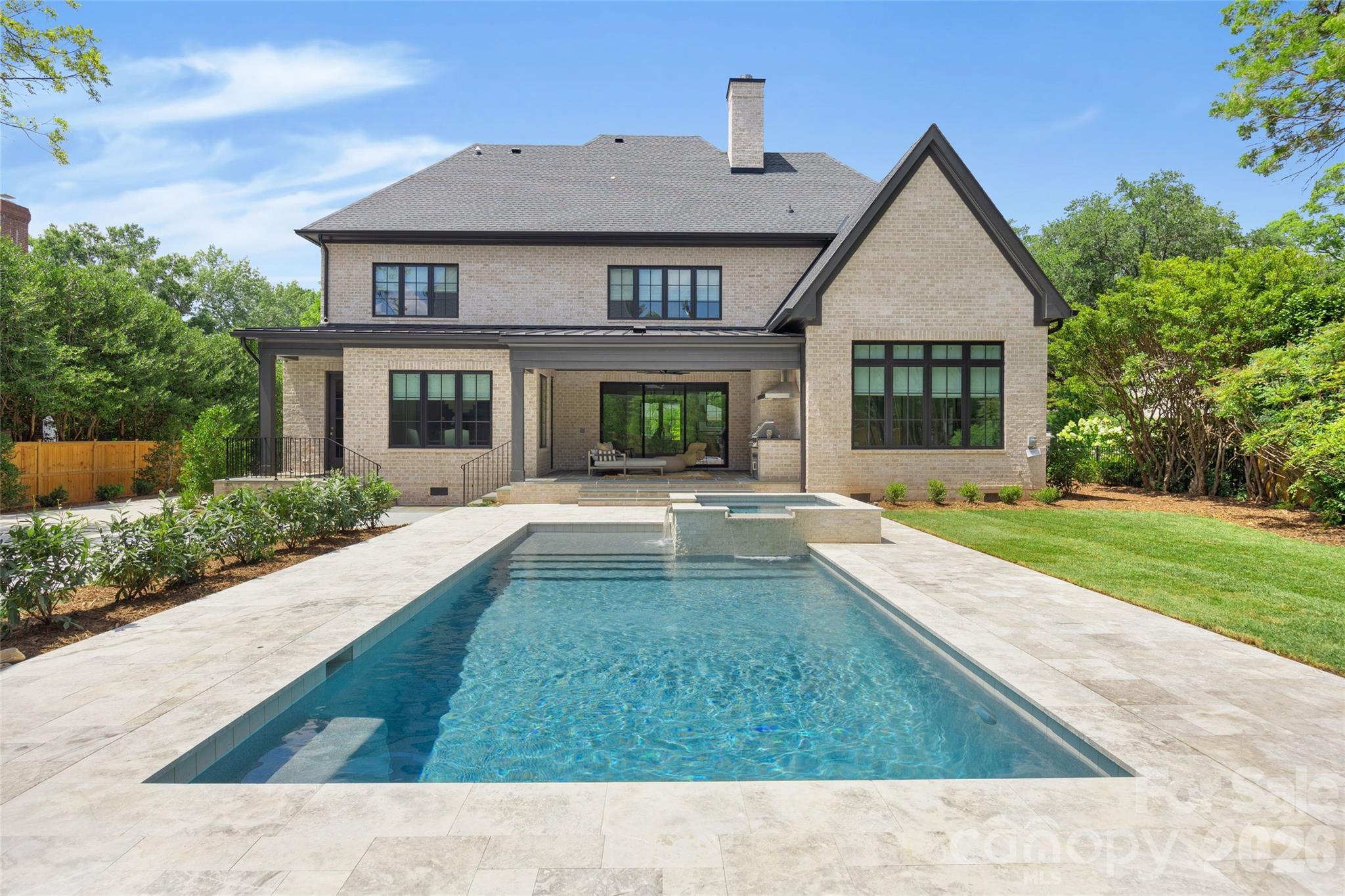 Drawn by acclaimed architect Robert Foster and built by Westwood Custom Homes, this Old Cotswold stunner delivers refined, modern sophistication in one of Charlotte’s most coveted neighborhoods.
A soaring two-story foyer with hardwood herringbone inlay sets the tone, complemented by bountiful natural light, curated interiors, and custom trim throughout. The chef’s kitchen features bespoke cabinetry, a 46" Wolf range, and a show-stopping scullery with exceptional storage, wine and beverage fridges, and a second dishwasher—designed for those who love effortless entertaining.
The Great Room is anchored by a wood-burning Isokern fireplace and opens through a retractable glass wall to a covered outdoor living space complete with a gas fireplace, built-in heaters, and a gas grill. A glamorous pool with an integrated spa creates seamless year-round indoor/outdoor living.
The main-level primary suite offers a vaulted ceiling, oversized windows with custom window treatments, and a spa-inspired ensuite with a soaking tub, dual vanities, and a zero-entry shower. The expansive walk-in closet includes an integrated washer and dryer, completing the retreat.
A main-level office with an adjacent bath doubles as a guest suite, while the second level offers three ensuite bedrooms and a flexible living space with a dry bar and dedicated half bath. The large laundry room adds ideal everyday functionality. A nearly 400-square-foot private suite over the garage provides additional space for guests or a secondary office.
1321 Ferncliff delivers elevated design, exceptional craftsmanship, and true resort-style living.