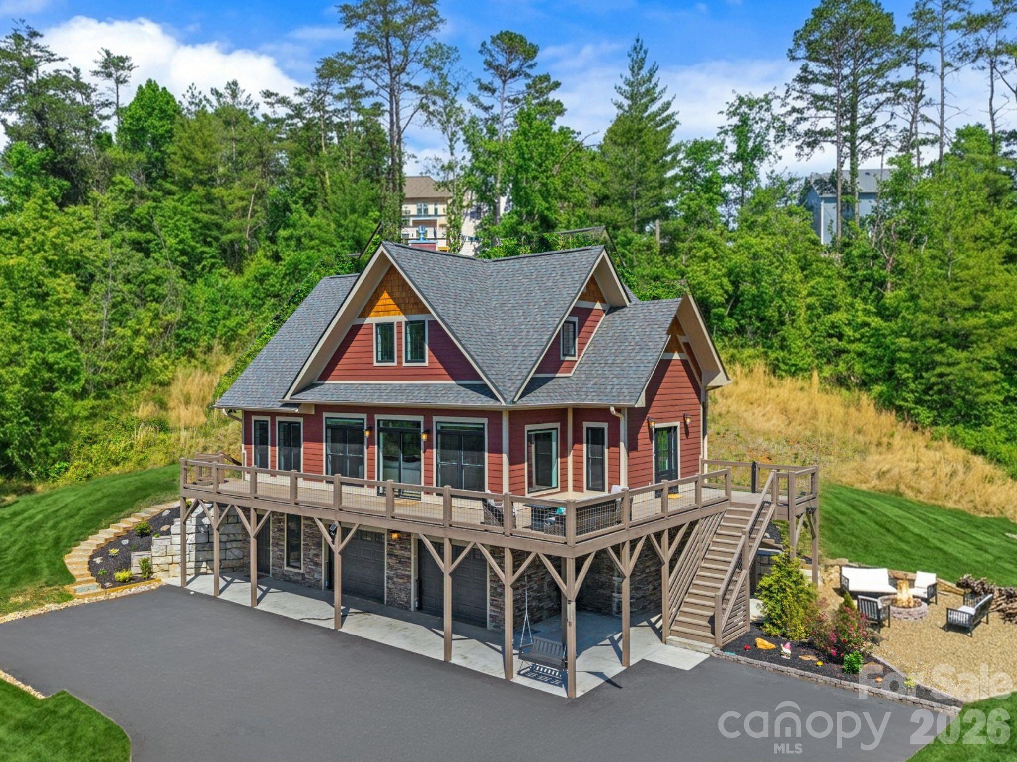 Like-new construction meets the quiet beauty of mountain living at this thoughtfully designed Weaverville home, set on over 1.7 usable acres within a peaceful community setting. Showcasing a warm Craftsman aesthetic, the home is filled with abundant natural light, where expansive windows and an airy open-concept layout create a living experience that feels both elevated and inviting. Anchored by a dramatic floor-to-ceiling stone fireplace, the main living area flows seamlessly into a beautifully appointed kitchen featuring sleek stainless appliances, a custom backsplash, a walk-in pantry, generous cabinetry, and an oversized breakfast bar designed for gathering and everyday living.
The spacious primary suite is conveniently located on the main level, while the upper level offers three additional bedrooms and a full bath. Custom-tiled showers and thoughtfully designed built-in closet systems elevate all three bathrooms and bedroom spaces with both style and functionality. A dedicated main-level office provides the ideal space for remote work or quiet study.
 Outside, curated landscaping enhances the natural beauty of the property, while the expansive wraparound deck creates the perfect setting for entertaining, relaxing, and taking in the peaceful surroundings. A beautifully crafted fire pit area further extends the outdoor living experience. The unfinished walkout basement, already plumbed for a future bathroom, offers excellent potential for expansion into additional finished living space. Located just minutes from Downtown Weaverville and convenient to Asheville, this property offers a rare balance of modern comfort, usable land, and everyday accessibility.
