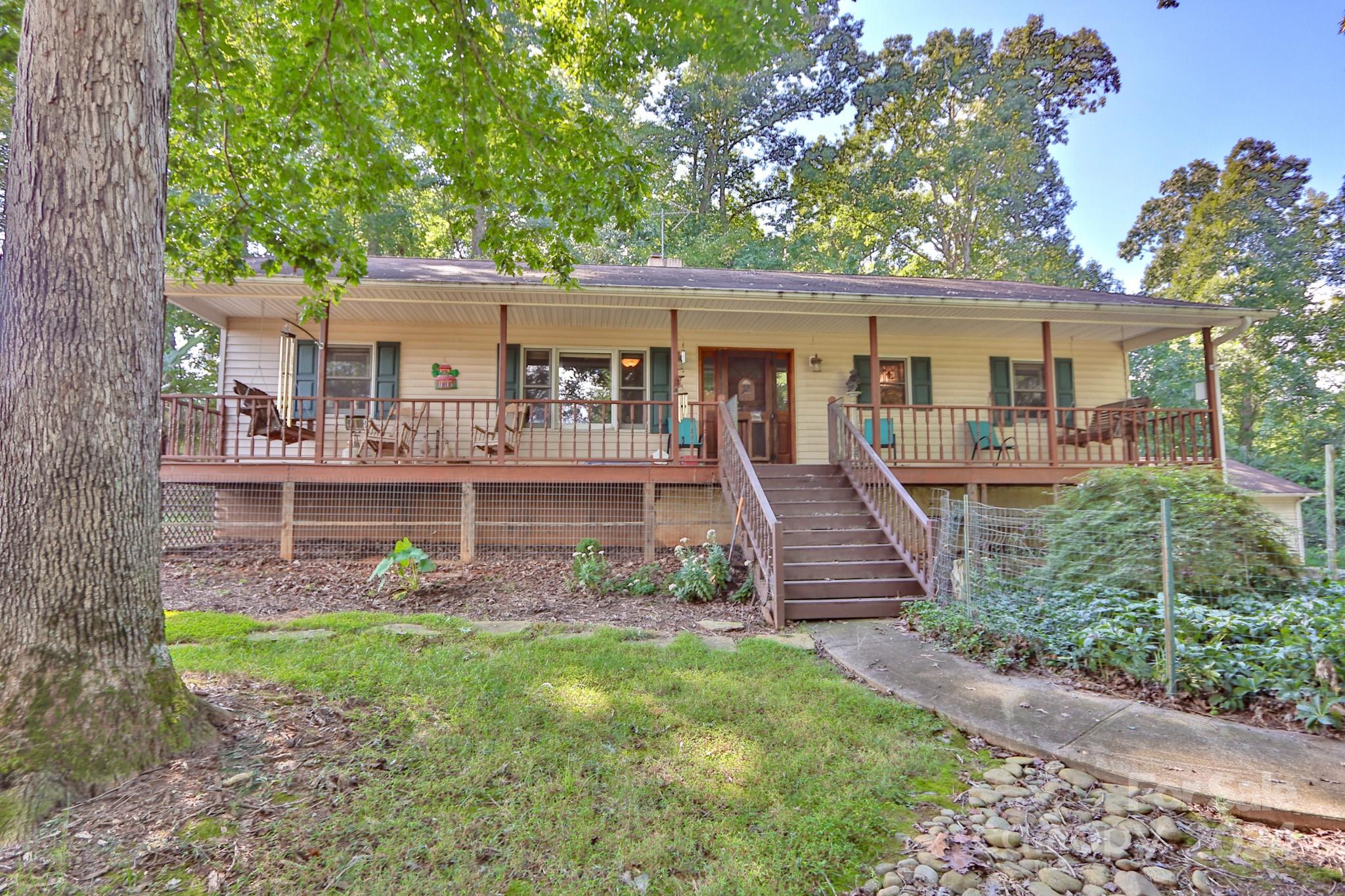 Best kept secret in Yadkin County with views of Pilot Mtn and Hanging Rock. This inviting 3BR/3BA ranch home offers a perfect blend of rustic charm & modern comfort. Come & sit on the HUGE rocking chair porch, take in the mountain views, gaze at the dazzling array of lush blossoms & landscape, amaze at the wildlife! Nestled on nearly 2 acres w/approx. an acre fenced. A mahogany, hand-crafted screen door welcomes you in.  Beautiful solid wood beams accentuate vaulted ceiling in living room. Dining room French doors lead to back deck with built in seating overlooking backyard & nature. Spacious kitchen w/cabinets made from trees on the property. A roomy primary bedroom w/large walk-in closet. Need more living area? Basement offers a bonus room, office, & full bath! Basement laundry room has utility sink & cabinets. FANTASTIC WORKSHOP for the hobby enthusiast w/over 1000 SQFT shop on it’s own power w/440V capabilities! Don't miss out on all this one has to offer. Schedule a tour today!