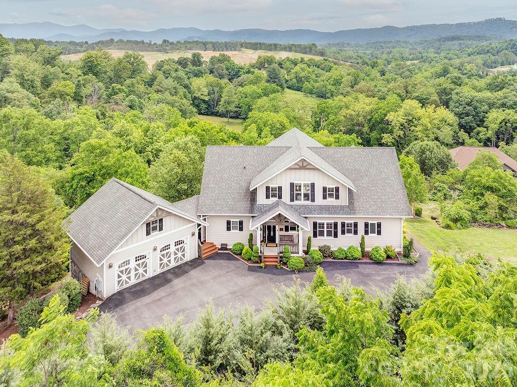 Welcome to a rare opportunity in the coveted and picturesque Alpine Meadows community of Weaverville — a magnificent, custom-built luxury residence where no detail was overlooked and no expense spared. Perched to capture breathtaking views from virtually every room, this home is the definition of luxury mountain living. Enjoy stunning mountain views, outstanding curb appeal, and access to a beautiful community pond stocked with fish, creating a peaceful setting you'll love coming home to.
Inside, custom details abound. White oak hardwood floors flow through the main living areas. Elegant Hubbardton Forge lighting fixtures adorn the hallways and living spaces, and lights throughout the home are on dimmers, creating the perfect ambiance at any hour. Custom Hunter Douglas power blinds grace the great room, allowing you to brighten or darken the room with the push of a button. The inviting living room features handcrafted oak and walnut built-ins and a gas fireplace finished with dramatic floor-to-ceiling custom slate and double mantles. Pocket doors, stair lighting, and thoughtful architectural touches distinguish every space. 
The gourmet kitchen is appointed with a Thermador gas range, Viking microwave, oven, and warming drawer, GE Profile refrigerator, and Zephyr exhaust fan. Under and in-cabinet lighting, stunning candelabra on a track lighting rail, sliding pantry drawers, deep pull-out self-closing drawers, raised dishwasher, and an island sink with garbage disposal make this space as functional as it is beautiful. Designed for seamless indoor-outdoor living, the kitchen opens to a delightful three-season room, the ideal spot to entertain guests or take in the surrounding mountain scenery. Expansive decks extend the living spaces outdoors, offering multiple areas for dining, relaxing, and enjoying the views. 
The spacious primary bedroom captures sweeping mountain views with walk-out deck access. Custom electric blinds cover the south wall of this bedroom offer day/night light control. This suite is connected by a large walk-in closet and dedicated home office/additional bedroom (no permanent closet, accessible from the home's hallway). The en suite bath showcases a grand stone-and-tile shower, custom tile work, and a commode room with double doors. 
Two large guest rooms with vaulted ceilings offer spectacular mountain views and comfort. The guest bath features striking fossilized wood tile. Stair lighting and a post light at the top of the stairs add elegance and safety. There is ample storage throughout the upstairs from the linen closet to the lighted, climate controlled attic storage behind the closets.
The 9ft high-ceiling lower level is anything but an afterthought and provides exceptional mountain views with walk-out stamped concrete patio and easy yard access. The large main area offers flexibility with space for a den, studio, or guest retreat. Flexible track lighting, views to the outside, and white oak LVP set the tone. The full bath is a showstopper: radiant heated floors, floor-to-ceiling tile, and a stone knee bench. A dedicated workshop with exterior access, water softener, closet storage, and a 48-in sidewalk leading to the ground level patio and separate basement utility garage, ideal for motorcycles or lawn equipment, round out this level.
The home is completely self sufficient featuring a whole-house generator, 1000-gallon propane tank, 5-zone HVAC with remote thermostat controls, and security system. The laundry room is a dream: machines on pedestals, a laundry sink, and built-in storage. The truly oversized 2-car garage has space for outdoor hobbies and equipment and includes pull-down attic access for additional storage. 
Surrounded by the natural beauty of the Blue Ridge Mountains, this magnificent home is a legacy property where every finish, system, and view has been thoughtfully considered. Properties of this caliber in WNC are few and far between. Schedule your private showing today.