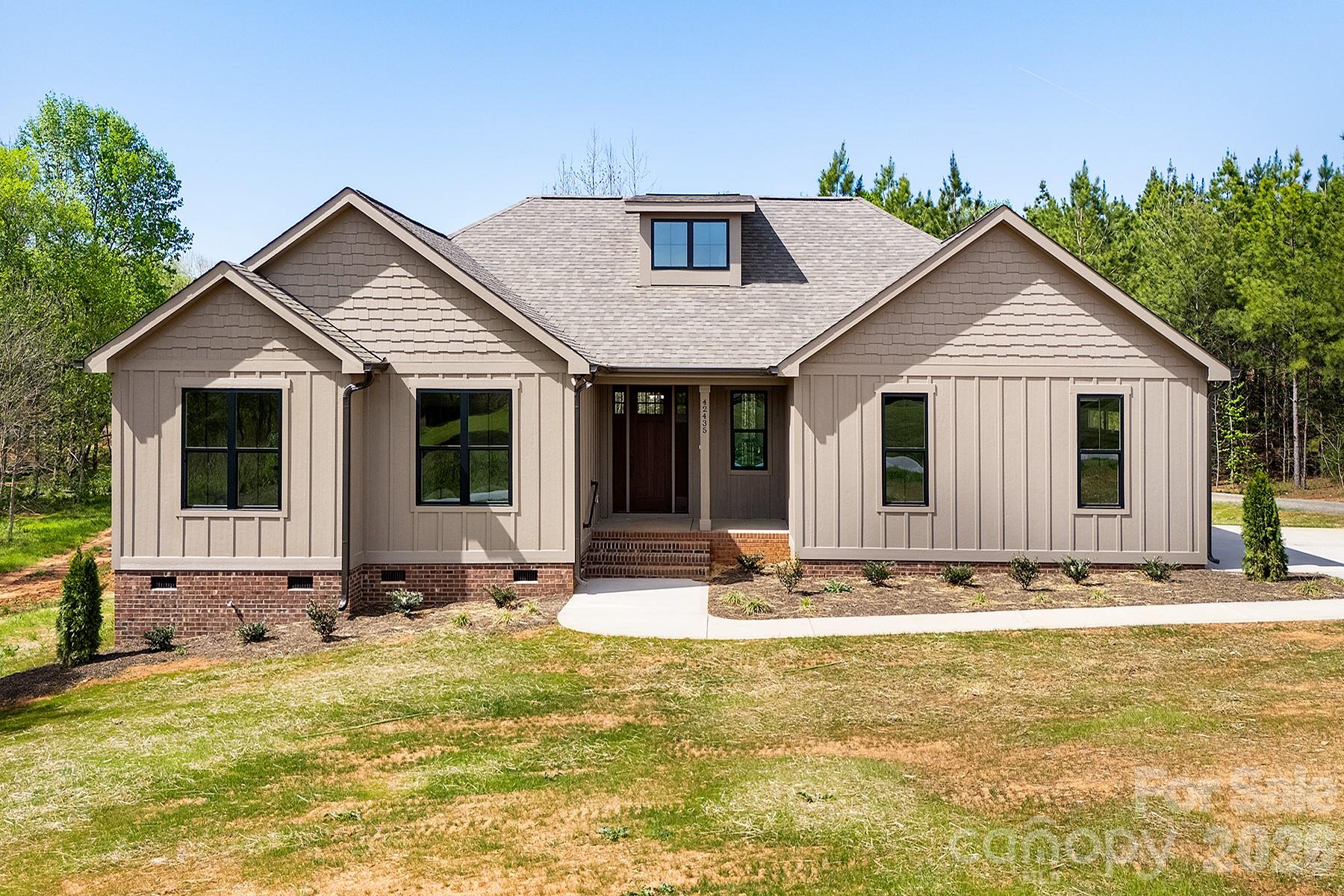 A rare blend of refined design, peaceful living, and close proximity to Lake Tillery, this stunning new construction home on 1.61 acres redefines modern country elegance in the heart of Norwood. Just minutes from the lake’s boating, fishing, recreation, and scenic shoreline, this 3-bedroom, 2-bath residence offers 1,727 square feet of sophisticated, open-concept living filled with natural light, soaring ceilings, and premium finishes throughout. The designer kitchen serves as a striking centerpiece, featuring a spacious island, sleek surfaces, white cabinetry, and stainless appliances that flow effortlessly into the living and dining areas, making it perfect for both intimate gatherings and elevated entertaining. Retreat to the primary suite, where a spa-inspired bath with a beautifully tiled walk-in shower, dual vanities, and generous closet space creates a true sanctuary. Thoughtful architectural touches, including warm wood ceiling accents and seamless indoor-outdoor transitions, enhance the home’s character and charm. Step outside to enjoy the covered front porch or unwind on the expansive rear covered porch overlooking a private, tree-lined setting that offers both serenity and space. Complete with a side-load two-car garage, concrete driveway, no HOA, and convenient access to one of the area’s most beloved lake destinations, this property delivers an exceptional lifestyle defined by comfort, privacy, recreation, and timeless style.