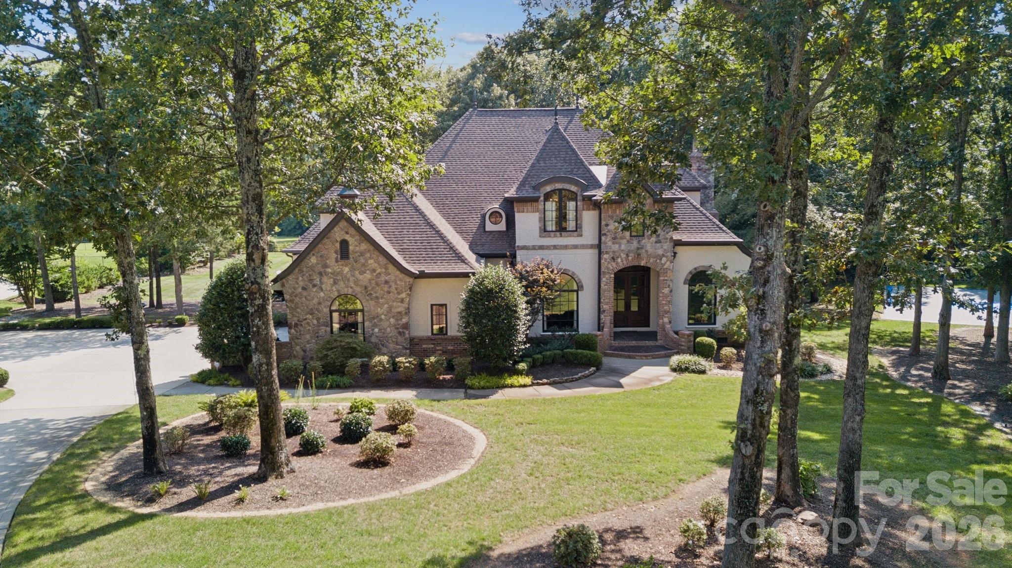 Welcome to the gated Woodhall community in Waxhaw! This custom-built French home is situated on a spacious 1.54-acre corner lot in the gated Woodhall community. The 4,405 sq ft residence features five bedrooms and three and a half bathrooms, offering an expansive and well-designed layout.

French doors introduce the home's charming architecture and stately presence creating an inviting first impression. The spacious foyer leads into the elegant living spaces, where hardwood floors, arched windows, and ornate architectural details seamlessly blend to display timeless sophistication. The formal dining room showcases a grand, elegant ambiance with its abundant natural light and charming architectural features. The open concept living room is anchored by a beautiful custom stone fireplace with a tube for the 8KTV. Custom stained beams compliment the hardwood floors with a 5.1 Dolby surround sound system in the ceiling.

The gourmet chef's kitchen boasts a spacious layout with ample counter space and cabinetry, complemented by the custom built-in refrigerator and gas range.  The primary bedroom suite is generously sized and features elegant decor, a custom shower and country tub, vaulted ceilings, with direct porch access to the beautiful expansive backyard.

The lush landscaping and expansive lawn provide a serene outdoor oasis, perfect for entertaining or enjoying private moments. The property also features a concrete basketball court, a Tesla charger in the garage, and a smart home system with commercial-grade Wi-Fi throughout. 
The upstairs features a unique guest suite and media room with pre-wired surround sound. 

This turn-key ready home offers an elevated living experience, with its spacious corner lot, charming architectural details, and abundance of luxurious amenities. Home is in the exceptional Marvin Ridge school district. Schedule your showing today!