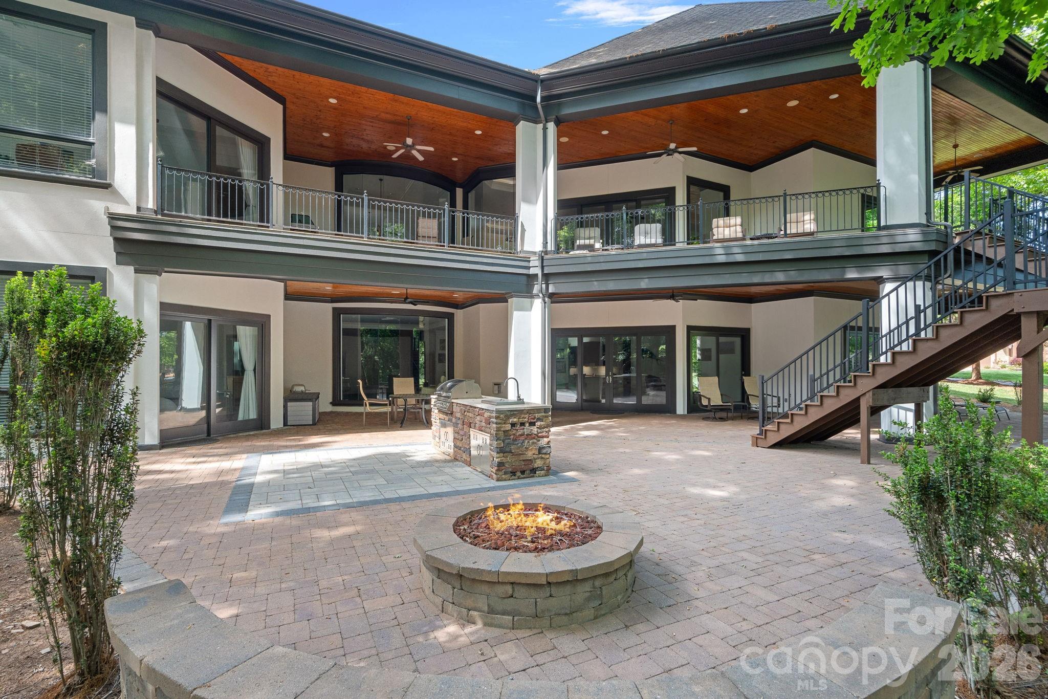 Situated on 1.3 acres in The Point’s prestigious Sturbridge Village, this two level waterfront estate offers views of Lake Norman and Trump National’s 13th fairway. Recently updated with NEW lighting, full interior and exterior paint, flooring and more, this home exudes refined elegance. Designed with five beautifully appointed bedroom spaces (permitted for four per septic) and over 6,300 SF of luxury finishes. Experience true open concept living as soon as you step inside. Custom curved floor to ceiling windows frame the exquisite views while vaulted ceilings on both levels give the home a light, airy feel. A true chef’s kitchen features NEW Cambria quartz countertops, NEW Thermador professional appliances, and NEW custom pantry with built-in wine cooler and bar cabinet. The main-level primary suite includes a spa-inspired bath, dual closets and private balcony access. Two additional bedrooms with ensuite baths and a private office are located on the main level. The lower lake level provides an opportunity for second living quarters with kitchen, theatre room, recreation area and two bedroom suites. Outdoor living shines with expansive covered terraces, outdoor kitchen, stone fire pit, private dock with deep-water access and room for a pool. Additional features include newly installed Trex outdoor staircase, a full home instant hot water system, oversized 3-car garage with plenty of guest parking, newer HVAC systems, and walk-in storage areas. Enjoy world-class amenities at Trump National Golf Club—golf, tennis, dining, fitness, social activities. NEW pickleball courts located right across the street.