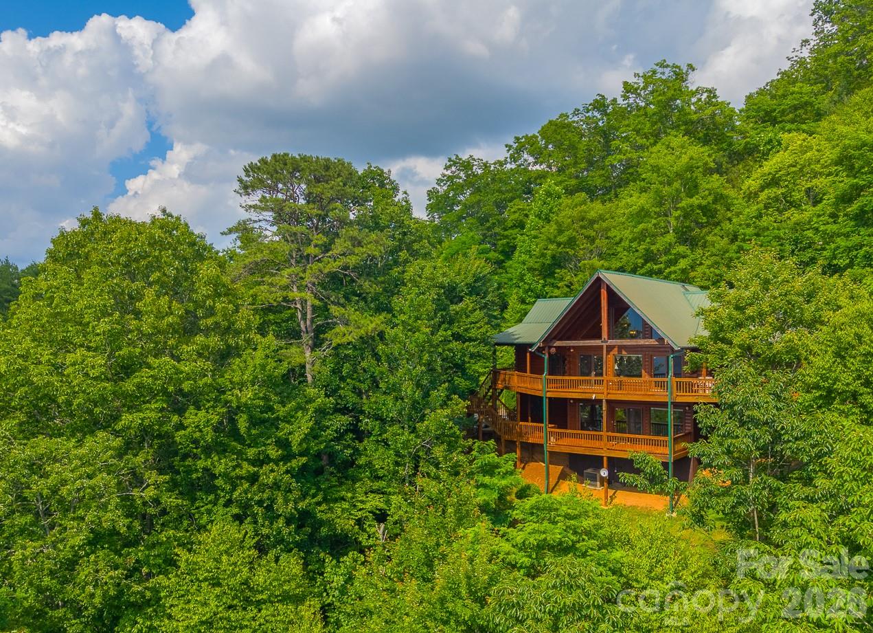 Step outside, breathe deep, and let the mountains do the talking.

Perched high above the valley in the coveted Beechwood community, this extraordinary log home was built around one thing: the view. From sunrise coffee on the deck to evenings spent watching the mountains fade into layers of blue, every day here feels like a retreat.

The moment you walk through the door, your eyes are drawn to the soaring wall of windows framing seemingly endless ridgelines. Vaulted tongue-and-groove ceilings, rich wood interiors, and a stunning stone fireplace create the warm, authentic mountain atmosphere buyers dream about but rarely find.

The expansive covered decks are where you'll spend most of your time. Start your mornings with coffee as the sun rises over the peaks. Enjoy cool summer breezes while dining outdoors. End the day with a glass of wine as the sky puts on a show and the lights begin to twinkle in the valley below. Rain or shine, these outdoor living spaces invite you to slow down and savor every season in the mountains.

Inside, the spacious main level offers comfortable everyday living with a primary suite, guest bedroom, open living area, dining space, and kitchen designed for gathering. Upstairs, the loft overlooks the great room below and provides the perfect spot for reading, working remotely, or accommodating additional guests.

The finished lower level creates an ideal second living area with a large family room, third bedroom, full bath, and two bonus rooms that offer flexibility for recreation, hobbies, home office space, or overflow sleeping accommodations. Whether you're hosting family for the holidays or welcoming vacation guests, there's room for everyone.

Lovingly maintained and gently enjoyed as a second home, this property offers the rare combination of authentic log cabin charm, breathtaking long-range mountain views, and exceptional vacation rental potential. With over 3,500 square feet of heated living area, multiple gathering spaces, and nearly 1,400 square feet of deck space, this isn't just a mountain home—it's the mountain lifestyle you've been searching for.

With over 3500 square feet of heated living space, three bedrooms, three baths, multiple bonus spaces, and nearly 1,400 square feet of deck and outdoor living area, this is the mountain getaway buyers envision when they dream of Western North Carolina.
