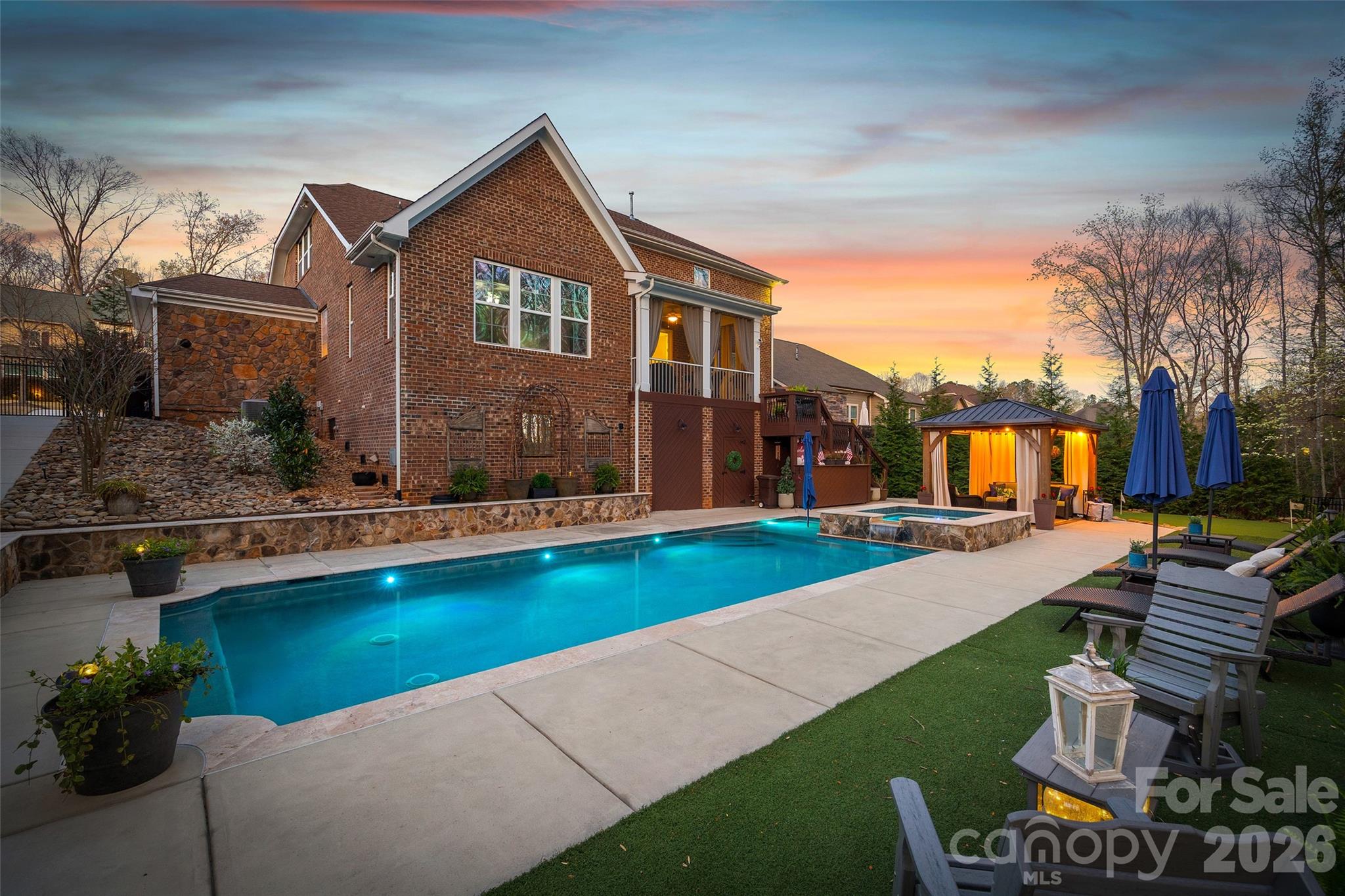 Nestled in a wooded backdrop, the immaculately maintained, full-brick home in prestigious Eppington South, features a heated pool with a hot tub as the centerpiece of this backyard retreat. You can feel the custom finishes from the moment you step in from the covered front porch, onto gleaming handscraped hardwoods that run throughout the entire home (no carpet). The entrance foyer is flanked by an office or flex space with gorgeous French Doors, and a dining room with a butler's pantry that leads into a chef's kitchen. An expansive island anchors the kitchen, which boasts a gas range with a wood hood, double ovens, microwave in the island, Frigidaire Gallery series stainless steel refrigerator (included), Rev-A-Shelf and additional cabinet pullouts, designer knobs, breakfast area, and more. The kitchen opens to the great room, which features a brick gas fireplace providing a cozy atmosphere, and the ample windows provide views to the tree-lined backyard. The oversized primary suite on the main floor is tucked away, and features ceiling trim, split-vanities in the bathroom, a tiled walk-in shower with a bench, soaking tub for evening relaxation, and dual custom owner's closets with convenient access to the laundry room. The laundry room provides loads of extra storage, and access through to the drop zone area with built-ins. The downstairs half bath has been upgraded with a custom vanity and designer tile on the walls, over board and batten wainscoting. The open stair rail leads you to a large upstairs loft area, and upstairs you'll find 3 bedrooms with walk-in closets, another generous bedroom or bonus space, 2 full bathrooms, and 2 walk-in attic areas for extra storage. As you head outside you start at a screened porch off the breakfast area, which is the perfect spot to enjoy your morning coffee. The uncovered deck space with a built-in grill center is perfect for entertaining, and offers great views of this outstanding backyard! The PebbleTec finish heated pool has a hot tub with a waterfall into the pool, providing a peaceful ambiance. There is turf around the pool for easy maintenance, and a pergola with a seating area to enjoy the shade. A golfer's dream with a putting green, or fun for the golf recreation novice. You'll find abundant seating around the pool, and even a pool area half bathroom, with storage for convenience. There is ample parking, including a three-car garage and an expanded driveway, and includes details such as landscape and accent lighting. The homeowners have maintained this home to perfection, adding additional landscaping and privacy trees in the front and backyard, Wi-Fi-controlled trim lighting, tinted windows for energy improvement, and more! Be sure to see the full list of seller upgrades. Eppington South has one of the most central locations in Fort Mill, just minutes from I-77, located right off Gold Hill Rd, and with low SC taxes and award-winning schools, look no further for your ideal Fort Mill home!