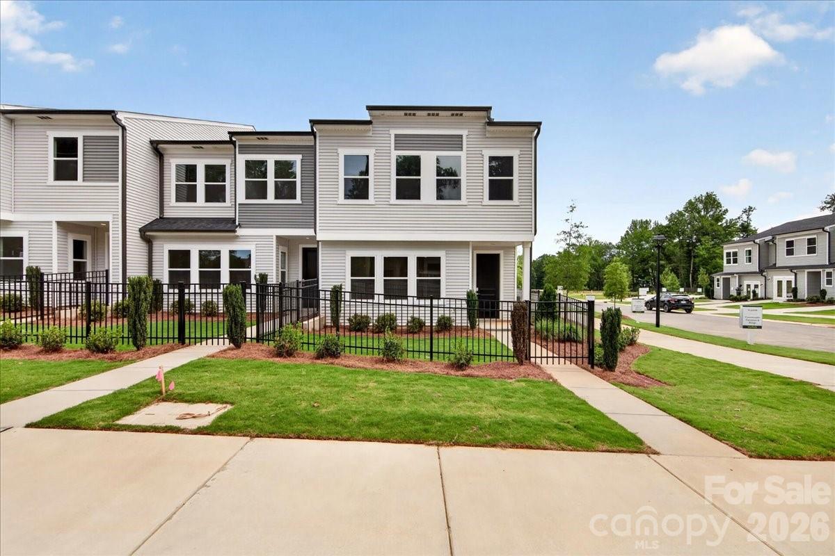 This three-bedroom, two-and-a-half-bath end-unit townhome at Amplitude opens to a fenced front yard and a two-bay rear-load garage, giving you outdoor space and a seamless arrival that's all your own. Inside, the chef-inspired kitchen anchors the main level with a GE electric range, a large single-bowl stainless sink paired with a Delta Essa Touch faucet, crisp white cabinetry, white quartz countertops, and a stunning Mythology Santorini tile backsplash that quietly steals the show. Upstairs, a versatile loft greets you before leading to the bedrooms. The primary suite features a walk-in shower with tiled walls, a dual vanity with white cabinets and drawers, and direct access to the walk-in closet. A secondary bath with dual vanity and a conveniently placed laundry room round out the upper level. Smart home features throughout, including wi-fi smart switches, a HomeSmart thermostat, a Ring doorbell, and prewired ceiling fan locations, mean the home is as connected as the location. With easy access to Uptown and Mint Hill and low-maintenance landscaping handled for you, this is the kind of ownership that fits into your life rather than demanding more of it. Photos are representative of model