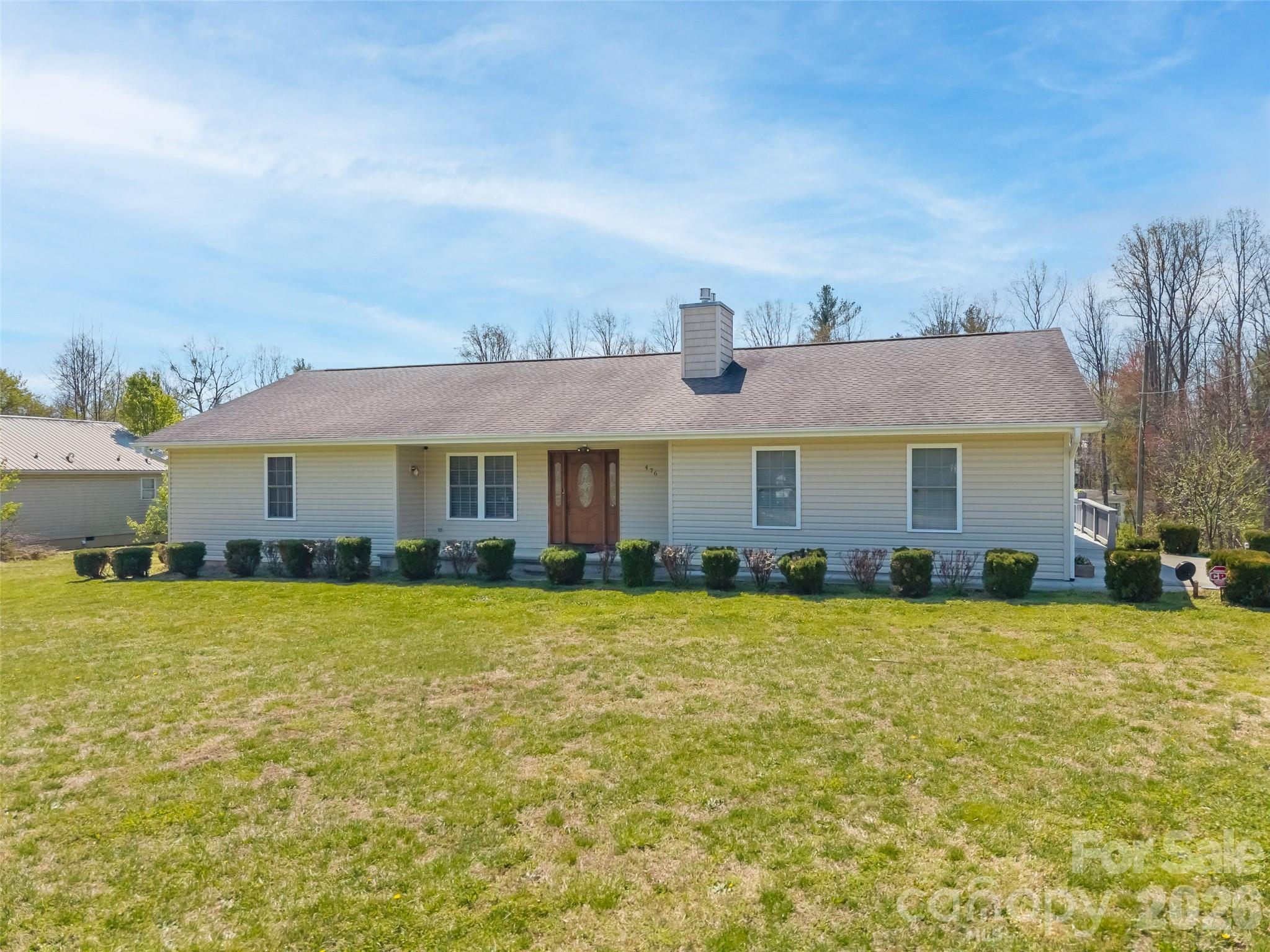Looking for true one-level living with privacy, space, and incredible extras? This exceptional property on 1.48 unrestricted acres has it all! The main level features three generously sized bedrooms, each with its own bathroom. The kitchen is a standout with extensive countertop space, a breakfast bar, LG InstaView refrigerator, double ovens, flat cooktop, roll-out drawers, built-in pantry, and a spacious eat-in dining area. A cozy living room offers a fireplace and Hunter Douglas remote-controlled shades. The main level also includes a convenient laundry room with sink, central vacuum system, and a whole-house Generac generator. The walk-out basement expands your living possibilities with a kitchenette and half bath, ideal for multi-generational living, guest space, hobbies, or recreation. Outdoor living includes a composite deck with partial awning and a covered front porch. The attached double garage provides extra storage. A major highlight is the large workshop featuring a full bathroom and space to accommodate an RV, perfect for hobbyists, collectors, or anyone needing flexible extra space. Enjoy fruit trees, privacy, abundant storage, and no HOA or restrictions, great for gardening, homesteading, and more. Conveniently located near I-26, shopping, dining, and downtown Hendersonville.
