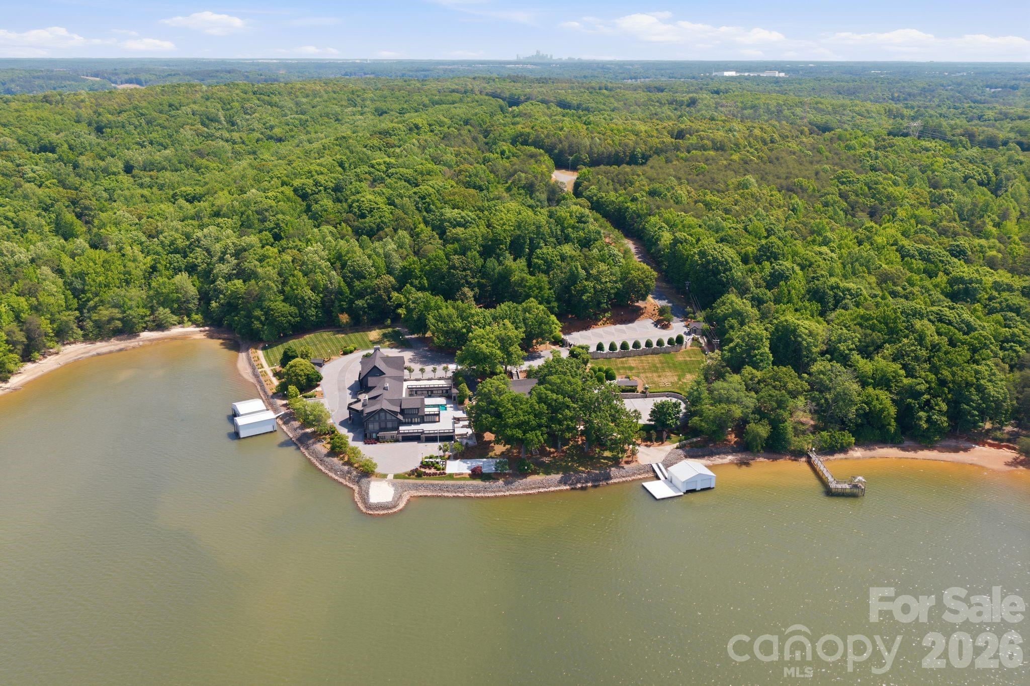 Welcome to a landmark Lake Wylie waterfront estate offering an extraordinary blend of architectural craftsmanship, privacy, and transformative potential just minutes from Charlotte. Set behind a private gated entrance with a guard house at the end of a winding, tree-lined drive, this residence is part of an exclusive 20+ acre compound with over 900 feet of pristine shoreline.

Encompassing more than 15,600 square feet and 13,000sf, respectively, the custom-built homes were constructed with the highest level of quality and structural integrity, showcasing timeless stonework, soaring vaulted ceilings, and grand-scale living spaces. While already impressive in scale and design, the homes present a rare opportunity to renovate and reimagine the interiors, allowing a discerning buyer to bring their own vision to life and create a truly bespoke luxury retreat.

The layout of the main house offers 6 bedrooms, including a private lower-level primary suite with his and hers en-suite bathrooms, walk in closets, private sauna and workout room, as well as lovely sitting room/den. 8 full baths and 2 half baths are thoughtfully positioned for both comfort and entertaining. Main level provides awe inspiring views of the water, soaring two story great room with a lavish stone fireplace, keeping room, and a large flex space that doubles as an art studio, craft space, office, or homework space with built ins galore! Outdoor living is equally exceptional, featuring a 40’ x 20’ saltwater pool, hot tub, and two private boathouses with lifts accommodating boats up to 34 feet.

The guest house offers another 13,000+sf and features 6 bedrooms, including a main-level primary suite, 7 full and 3 half bath providing generous accommodations for family and guests alike. This home was also built with superior quality and enduring materials, creating a strong foundation for a modern transformation.

A standout feature of the guest house is the fully finished basement with a complete second kitchen, ideal for extended living, entertaining, or creating a private guest residence. The outdoor experience is equally compelling, with a private boathouse equipped with a lift for a boat and two jet skis—offering effortless access to Lake Wylie’s coveted waterfront lifestyle.

Beyond the residences, the lifestyle is unmatched. Residents enjoy a lighted waterfront walking path along the shoreline, a basketball court, shuffleboard area, and even a private helipad—all designed to elevate everyday living into a resort-style experience. The property also includes a walk-in commercial cooler and parking for over 40 vehicles, ideal for hosting on a grand scale.

Adding to its rarity, an adjacent 15-acre parcel is available, offering the flexibility to expand the estate for ultimate privacy or pursue a development opportunity with conditional approval for up to 32 residential lots.

Located just 20 minutes from Charlotte Douglas International Airport and 30 minutes from Uptown Charlotte, this is a once-in-a-generation opportunity to own and transform one of the most significant luxury waterfront properties on Lake Wylie. Cross Reference MLS 4388347.Adjacent 15 ac parcel is available PIN 19936102