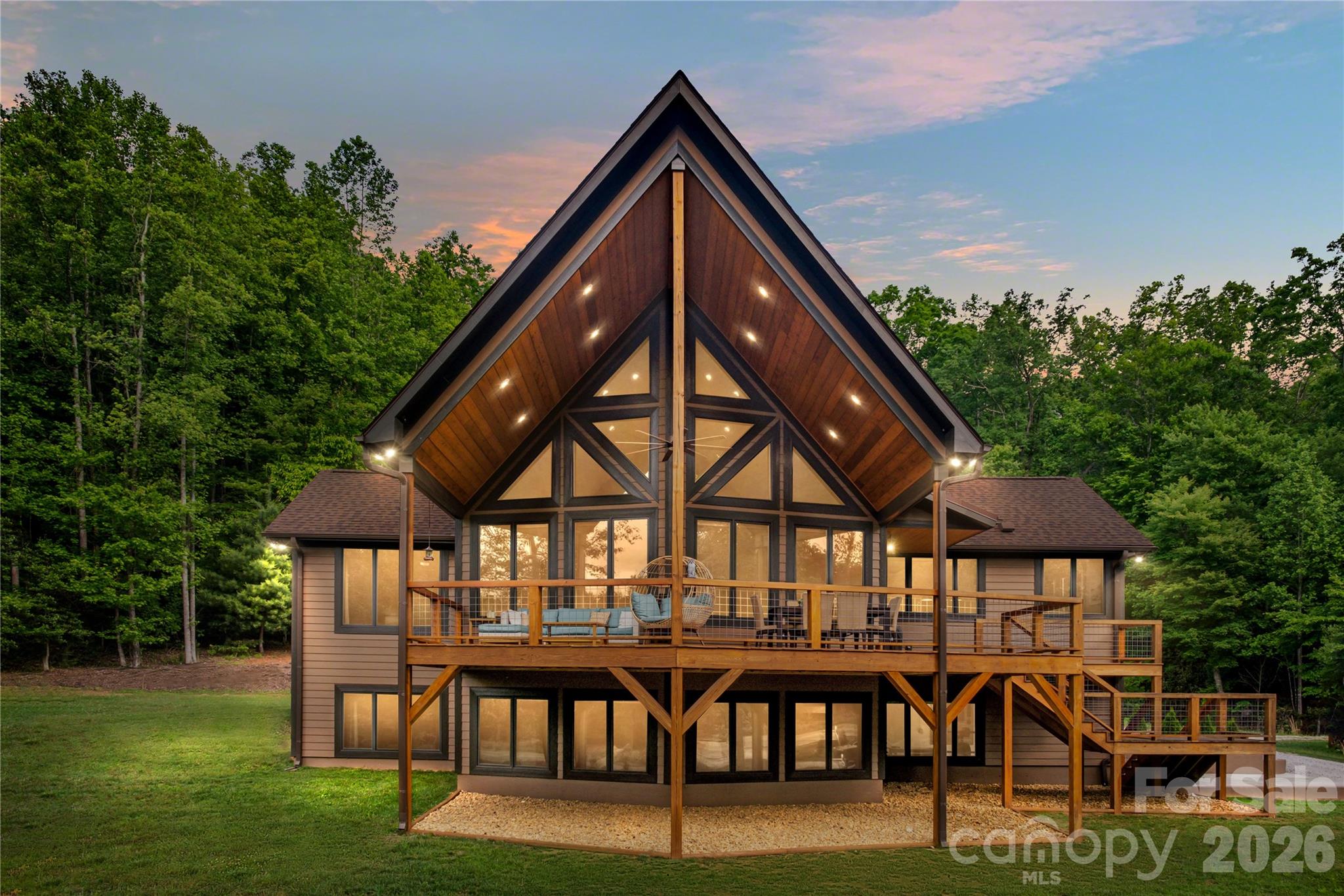 Welcome to your mountain-lake retreat near beautiful Lake James, North Carolina, where custom craftsmanship, natural beauty, and investment potential come together on a gorgeous 1.8-acre mostly level lot with winter lake views PLUS located in vision distance to public lake access and boat launch. Perfectly positioned near thousands of acres of state and national park land, the Blue Ridge Mountains, and the vibrant city of Asheville, this turnkey custom-built home offers the ideal blend of relaxation, adventure, and modern comfort. This stunning Australian timber oil-well stained home features over-the-top warmth and character with real 6-inch hickory hardwood floors on both levels, soaring cathedral ceilings, oversized windows that flood the home with natural light, and an inviting gas fireplace anchoring the spacious living room. The open-concept kitchen and dining area was designed for entertaining and everyday living alike, featuring stainless steel appliances, custom hood vent, tile backsplash, center island, and a large combination laundry room and pantry for exceptional storage and convenience. The main level offers a spacious primary suite with private ensuite bath featuring dual quartz vanities, custom tiled shower with rain head, and private water closet, along with an additional bedroom and full bath. Downstairs, the daylight basement provides incredible flexibility with two additional sleeping areas, a third full bath, and a large open family room perfect for guests, recreation, or additional rental accommodations. The one-car garage includes an electric vehicle hookup and is currently utilized as a home gym. One of the standout features of this home is the breathtaking covered front deck with tongue-and-groove cathedral ceiling, the perfect place to enjoy mountain air, seasonal lake views, coffee at sunrise, or evenings with friends and family. Outside, enjoy a beautifully maintained backyard complete with a lighted fire pit area, plentiful parking, and a sizable storage building. The home has 4 BEDROOMS with a county septic permit for 3.
Additional highlights include:
• No HOA
• No city taxes
• Well and septic system with no water or sewer bills
• Proven short-term rental history
• Furnishings negotiable for a fully turnkey opportunity
• Walking distance to public lake access and boat launch
Whether you are searching for a full-time residence, vacation getaway, or income-producing investment property near Lake James, this one-of-a-kind home offers an exceptional opportunity to own a slice of Western North Carolina paradise.
