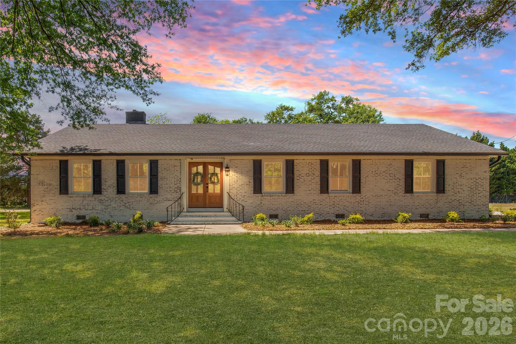 Welcome home to a rare blend of timeless construction and modern transformation—this fully renovated brick ranch on 1 acre offers approximately 2,500 square feet of thoughtfully designed space where comfort, flexibility, and style come together effortlessly.

From the moment you pull into the circular driveway, there’s a sense of arrival. The stately brick exterior and double front entry doors create a warm, inviting first impression that hints at the upgrades waiting inside.

Step through the doors and imagine the rhythm of daily life unfolding. Mornings begin in the beautifully updated kitchen, where granite countertops, an eat-in breakfast area, and bar seating make it easy to sip your coffee, pack lunches, or gather with family before the day begins. Just beyond, the formal dining room is ready to host everything from holiday dinners to casual weeknight meals that turn into lingering conversations.

The spacious living room becomes the heart of the home—perfect for movie nights, game days, or simply unwinding at the end of the day. With fresh paint, new flooring, new windows, and new doors, every space feels crisp, clean, and move-in ready, while upgraded black finishes, wide baseboards, and enhanced trim work add a subtle layer of modern sophistication throughout.

Designed with flexibility in mind, this home features two primary suites, offering an ideal setup for multigenerational living, extended guests, or a private retreat. Each suite provides ample bathroom space and walk-in closets, giving everyone room to spread out and stay organized. Two additional bedrooms and a full bath ensure there’s space for family, guests, a home office, or hobbies.

Step outside and picture weekends spent enjoying your 1-acre lot—whether it’s gardening, entertaining, or simply soaking in the peace and quiet. The 2-car garage and additional outbuilding open the door to endless possibilities: a workshop, storage for equipment, a creative studio, or even your next big project.

Location adds another layer of convenience and lifestyle appeal. Situated within easy reach of Charlotte, Monroe, and Lancaster, commuting, shopping, and dining are all within a comfortable drive. When it’s time to play, you’re just minutes from the excitement of Charlotte Motor Speedway and Carowinds, or the natural beauty of Forty Acre Rock Heritage Preserve and Andrew Jackson State Park.

This home truly delivers the best of both worlds—the solid craftsmanship of a 1960s-built home paired with the updates and finishes today’s buyers are searching for. With its renovated interior, spacious layout, 2 primary suites, and 1-acre setting, this property offers the space, comfort, and versatility to fit a variety of lifestyles.

If you’ve been searching for a move-in ready home near Charlotte with room to grow, this one is ready to welcome you in and make itself part of your story.