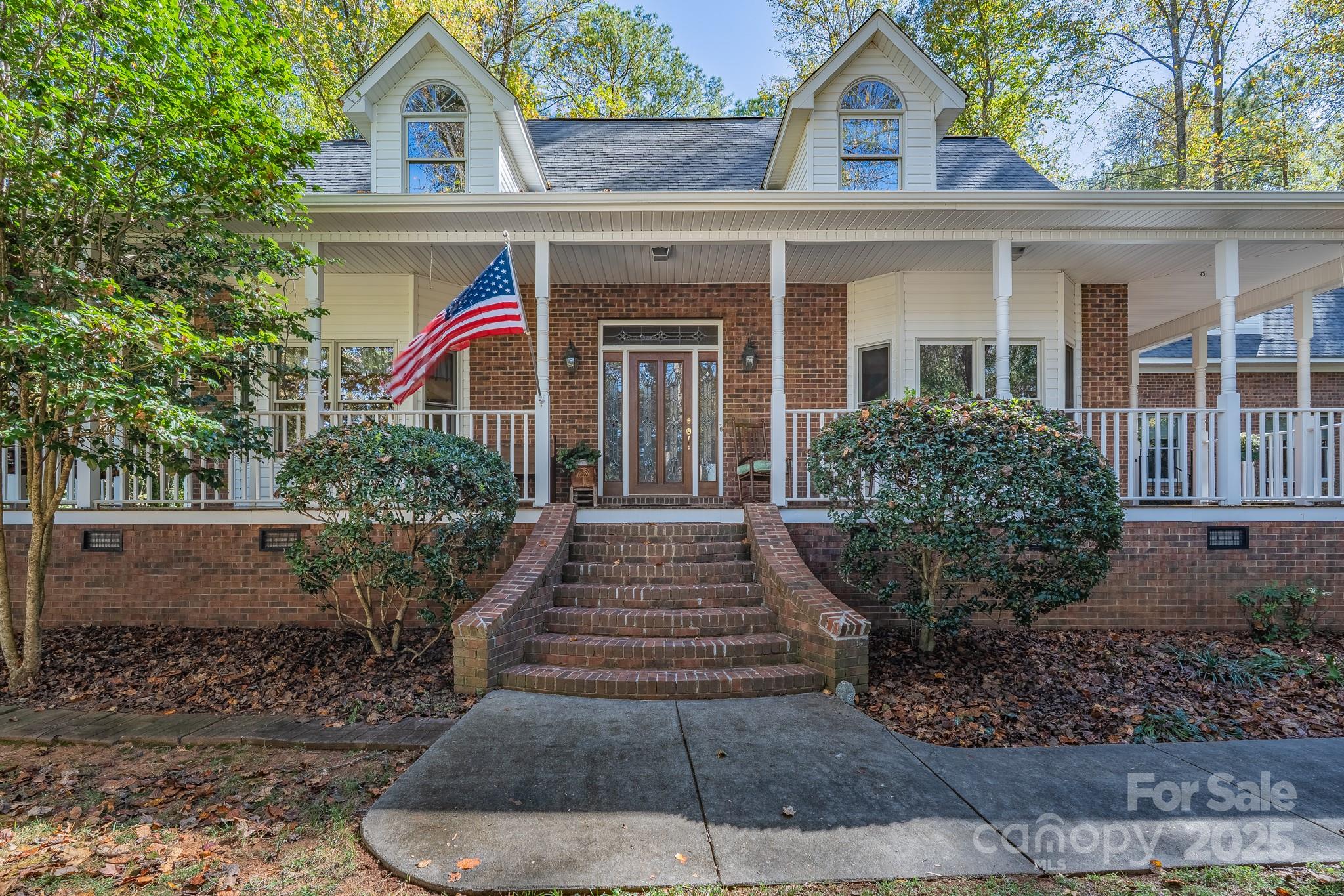 Sitting on top of the hill and in the middle of 1.49 wooded acres, this classic home is ready for new owners after having been well-maintained and loved by the original owners for the past twenty-seven years.  Walking up on the wooden front porch and overlooking the property, envision yourself enjoying the peace and calmness this property provides.  The white kitchen provides wonderful space for preparing meals and overlooks the family room, with fireplace.  Entertaining will be enhanced with a breakfast area in the kitchen, as well as a separate dining room with an entrance to the wrap-around porch.  The main level primary bedroom suite with spacious en-suite bath is sure to check a box on your list.  The living room can serve many purposes, including a nice space for a home office.  A large laundry room on the main level is sure to be enjoyed.  Upstairs boasts two additional generously sized bedrooms and a full bath.   A bonus room, with a separate entrance, provides fabulous space and privacy.   Outdoor entertaining will take on new meaning when you walk out to the screened porch!  With almost six hundred square feet, this space will be a haven for you and your guests to enjoy for the majority of the year.  Sit down and enjoy the views with your morning coffee or relax at the end of a busy day in this beautiful spot.  As you take a stroll on the property, make note of the variety of trees, shrubbery, and flowers.  Springtime will bring a bounty of blooms for you to enjoy.   An oversized double garage has room for vehicles, storage, and work area.  An additional outbuilding provides storage space – especially for your equipment and tools.  This home is equipped with a central vacuum throughout and Comporium security system on all windows and doors.  Located in Meadow Lakes and with no city taxes, 1085 Pinecrest Drive is ready to welcome you!