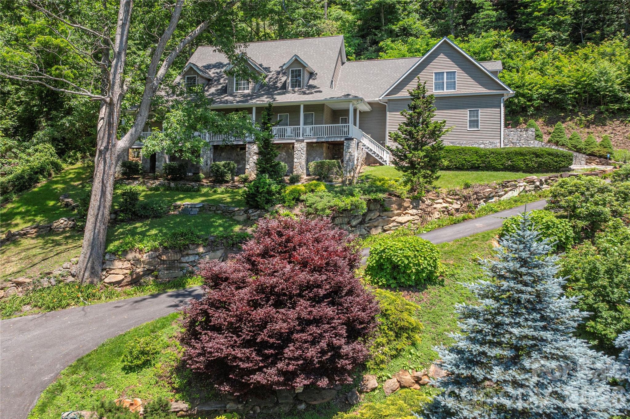 Located in the gracious & friendly gated community of Junaluska Highlands, this scrupulously maintained mountain home offers long-range and year-round views, mature landscaping, and easy access in every season. The thoughtfully designed floor plan blends contemporary style with traditional warmth. The kitchen will make the fussiest gourmet happy. It features a double oven - one of them convection- a 5-burner gas cooktop, and abundant workspace for cooking and baking. The formal dining room, with its gorgeous chandelier, completes the epicurean picture. Gather around the stone gas fireplace in the living area with family and friends, or embrace outdoor living on the back terrace or front veranda. The main level includes a spacious primary suite plus an office/den with an additional bath. The upper level offers two en-suite bedrooms, a second kitchen, and a second laundry. Enjoy the flexibility of multiple bonus spaces, including a playroom and additional flex rooms—ideal for guests, live-in help, or multi-generational living. Additional highlights include custom wood shutters, zoned HVAC, extensive storage throughout, and an oversized garage with space for a workshop or a golf cart. All of this in a friendly neighborhood setting.