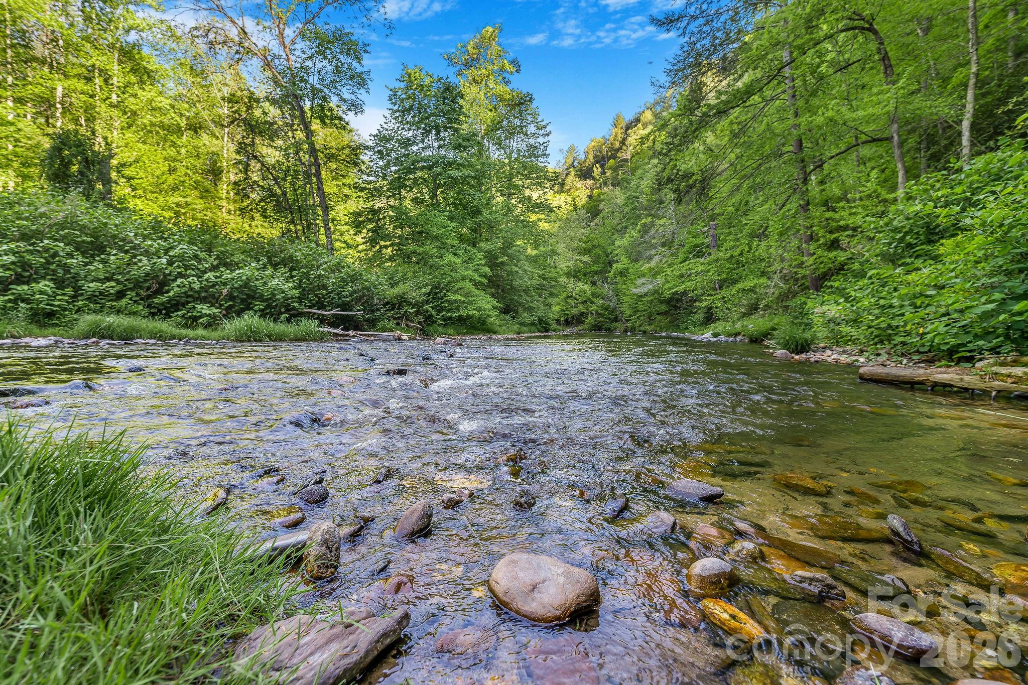 Own a rare slice of paradise with 240 feet of private frontage on the highly sought-after Delayed Harvest waters of Shelton Laurel River. Spanning nearly 6 unrestricted-feeling acres, this one-of-a-kind mountain retreat offers the perfect blend of adventure, privacy, and flexibility. Enjoy exclusive access to the river for trout fishing, tubing, swimming, or simply relaxing by the water, plus an additional 2.5-acre community riverfront common area just upstream.

Whether you're dreaming of a mountain getaway, short-term rental investment, or future cabin build, this property is ready to go. Light restrictions allow for a minimum 700 sq ft build and even permit camper use up to 6 months per year—ideal for hassle-free weekends in the mountains. A gated keypad entrance adds peace of mind, while a 2-bedroom perc permit is already on file. Electricity and high-speed internet are available at the driveway, and low annual POA fees cover road and common area maintenance.

Explore the property’s existing roughed-in hiking trails, complete with color-coded trail markers, benches and fire pits, or venture out to nearby outdoor destinations including the Laurel River Trail just minutes away and the Appalachian Trail only 12 minutes from your doorstep. The charming town of Hot Springs is a quick 15-minute drive for dining, shopping, and soaking in local mountain culture.

With seasonal mountain and river views, endless recreation, and short-term rentals allowed, this is the kind of property buyers wait years to find.
