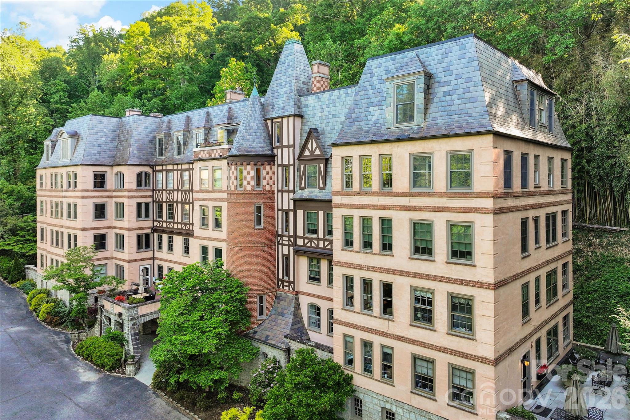At the pinnacle of the historic Longchamps building, this exceptional penthouse captures the romance of old-world architecture paired with the ease of contemporary living. One of Asheville’s treasured residential landmarks, Longchamps offers a level of character and distinction rarely found today, and this residence stands as one of its most remarkable offerings. Spanning approximately 2,477 square feet, the home is filled with an airy elegance that feels refined and welcoming. Rich architectural details, curated built-ins, and beautifully proportioned rooms create an atmosphere that is sophisticated without feeling formal. At the heart of the residence, the expansive living room invites conversation and quiet evenings alike, with a fireplace serving as a warm focal point and adding to the home’s timeless appeal. The kitchen has been thoughtfully updated to complement the residence’s historic character while providing modern comfort and functionality. Designed to transition effortlessly from casual mornings to intimate entertaining, the space balances style and practicality with ease. A private library offers a serene escape ideal for reading, creative pursuits or working from home, while an adjoining bonus space connected to one of the bedrooms introduces additional flexibility. Arranged as a sitting room, it could easily become a luxurious dressing area, expanded wardrobe space or future bath depending on one’s vision. Perhaps the most captivating feature is the penthouse’s exclusive terrace, an extraordinarily rare amenity within Longchamps. Tucked above the cityscape, this secluded outdoor retreat feels reminiscent of a Parisian rooftop garden, offering a tranquil setting for morning coffee, evening wine or simply taking in the quiet beauty of the surrounding neighborhood. Intimate and inviting, it lends the residence an unmistakable sense of warmth and belonging. Steeped in Asheville history and defined by its French-inspired architecture, Longchamps has long been regarded as one of the city’s iconic addresses. This penthouse presents a rare opportunity to own a residence that seamlessly blends heritage, privacy, and understated luxury in an enduring and sought-after setting.