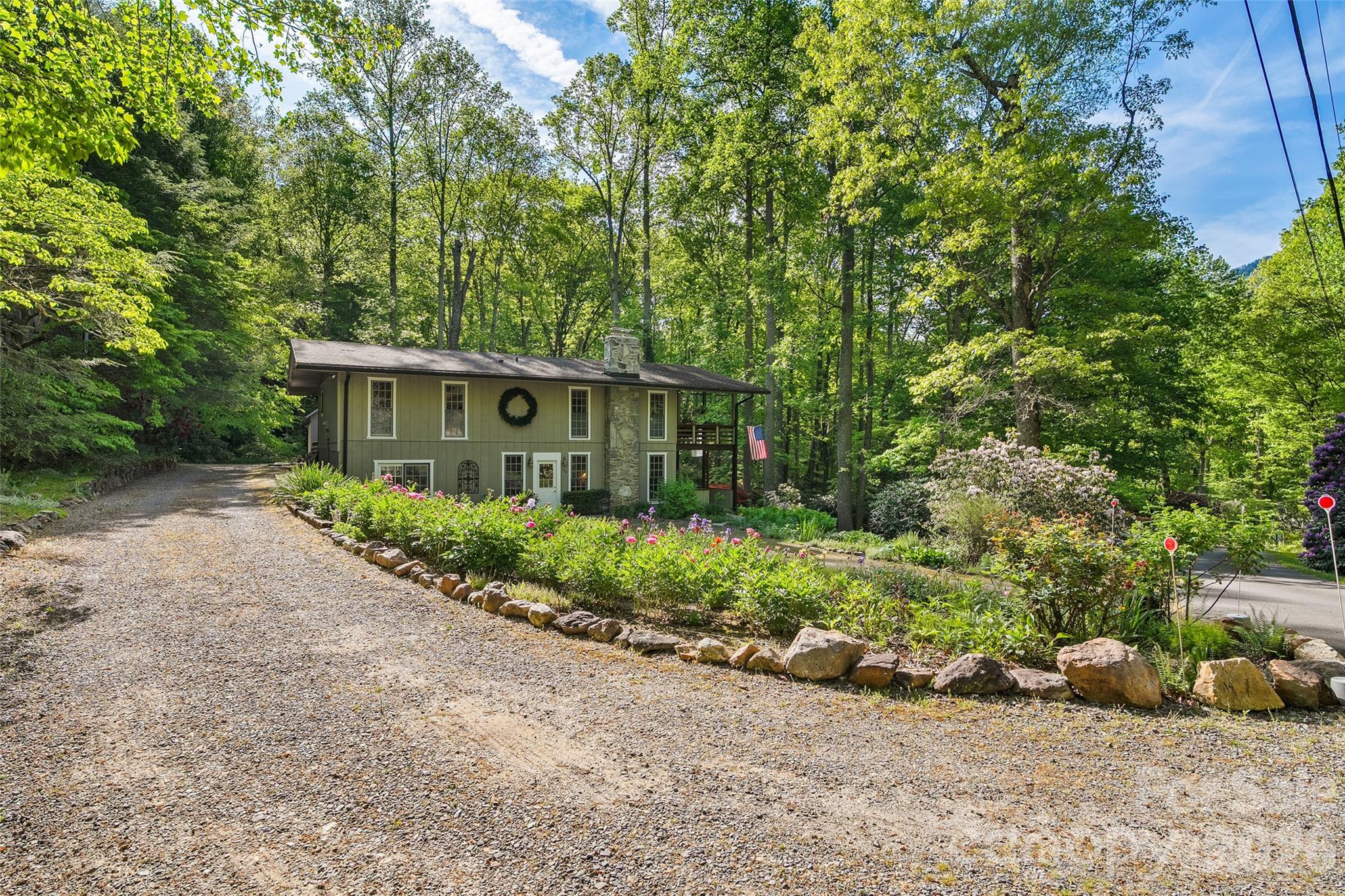 134 The Trail, tucked among lush, mature landscaping and surrounded by the natural beauty of the mountains, this one-of-a-kind retreat offers privacy, character, and exceptional functionality. Conveniently located just a few minutes from the Maggie Valley Country Club as well as just minutes from the heart of downtown Maggie Valley. Warm wood finishes, expansive built-ins, a stunning stone gas log fireplace, and a downstairs wood stove create a cozy, inviting atmosphere that feels perfectly suited for mountain living. Large windows throughout the main level bring the outdoors in, filling the space with natural light and peaceful wooded views.

The thoughtfully designed layout features comfortable bedrooms, a dedicated office/flex space, and multiple indoor and outdoor gathering areas. French doors open to a spacious covered deck where you can enjoy cool mountain evenings, morning coffee, or simply relax surrounded by nature. The workspace in basement is heated and is considered ‘unfinished’ and is perfect for projects or additional storage. The detached 3 car garage offers abundant space for hobbies, equipment, including additional storage space above with direct access from the side of the garage. 

Outside, the beautifully landscaped grounds feel like a private garden sanctuary with vibrant rhododendrons, winding walkways, and mature trees creating a truly serene setting. Whether you are looking for a full-time residence, mountain getaway, or a property with room to spread out and enjoy the outdoors, this home delivers a rare combination of charm, privacy, and practicality in a picturesque Maggie Valley setting.