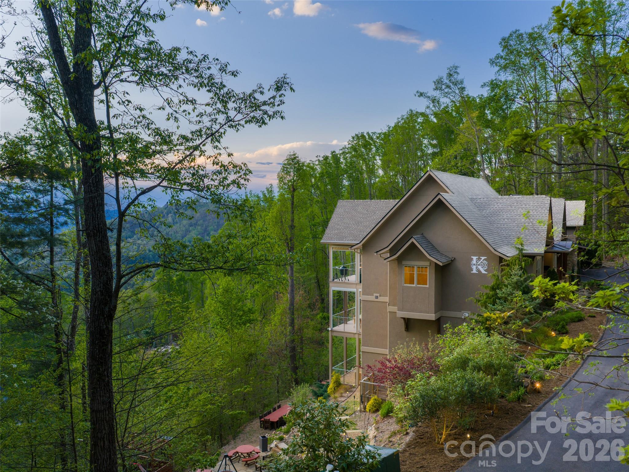 Stunning Reynolds Mt. home located on 3.5 acres complete with private hiking/walking trails. Offering complete privacy and security,  with western facing layered mountain sunset views of the Blue Ridge Mts from every room. Level driveway, 3 car garage with electric charging station and storage room. Expansive Great Room with Chef's Kitchen, two bedroom suites with large laundry room allows total main level living if desired. Front door offers one step entry.  Guest apartment/ in-law suite with private entrance complete with kitchenette, full bath and large closet. This Guest Apartment offers total privacy from the main house.  Two guest suites, family room with fireplace and private deck on lower level. Whole house generator, professional landscaping. Reynolds Mt. is located in desirable north Asheville near Grocery Store Row, and 10 minutes from downtown Asheville galleries, rooftop restaurants and shopping. Enter through a private custom-designed  gate which can be secured when home is unoccupied. Surrounded by nature, the home provides warmth and understated luxury. Terraced outdoor entertainment area perfect for parties/entertaining.