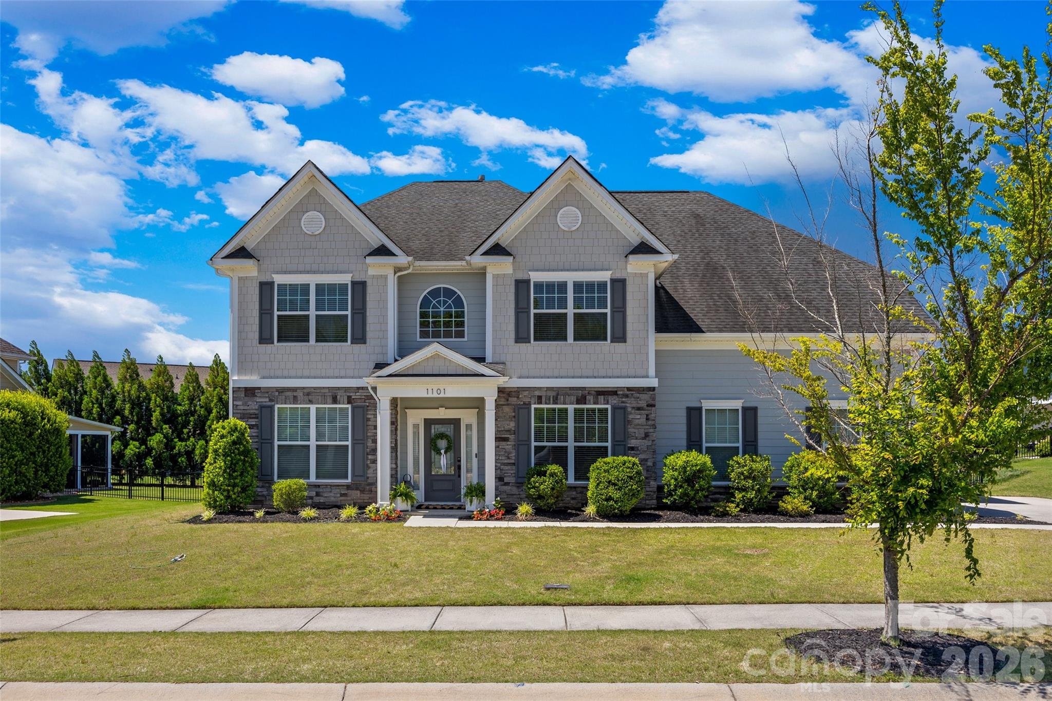 This spacious and beautifully appointed home offers over 4,000 square feet of warm, family-oriented living with a layout designed for both everyday comfort and entertaining. Positioned on a desirable lot with a large flat backyard lined with mature trees for added privacy, this home combines space, functionality, and a relaxed lifestyle in one of Fort Mill’s most amenity-rich neighborhoods. Built in 2018, this 5-bedroom, 4.5-bath home features a thoughtful floor plan including a main-level guest suite with a full bath that is ideal for visitors, multigenerational living, or anyone needing access without stairs. At the heart of the home is the expansive living room with stunning coffered ceilings that opens seamlessly to the bright white kitchen featuring stainless steel appliances, gas cooktop, oversized island, walk-in pantry, butlers pantry and generous gathering space.  Upstairs, the oversized primary suite offers a peaceful retreat with its own sitting room and dual walk-in closets. Updates include a covered rear patio addition creating the perfect place to relax and enjoy the private backyard setting.  The exterior offers timeless transitional styling with a deep front setback, large flat front yard, extended driveway, and rare 3-car garage. Residents of Massey enjoy exceptional amenities including a resort-style pool with lazy river, water slide, lap lanes, clubhouse, fitness center, playgrounds, walking trails, and community gathering spaces. The neighborhood is known for its architectural variety and charm, creating a streetscape that feels established and inviting rather than cookie-cutter.  Conveniently located near Hwy 521 and I-77 with restaurants, shopping, and a new Harris Teeter coming nearby, this home offers the perfect balance of convenience, community, and space to grow.