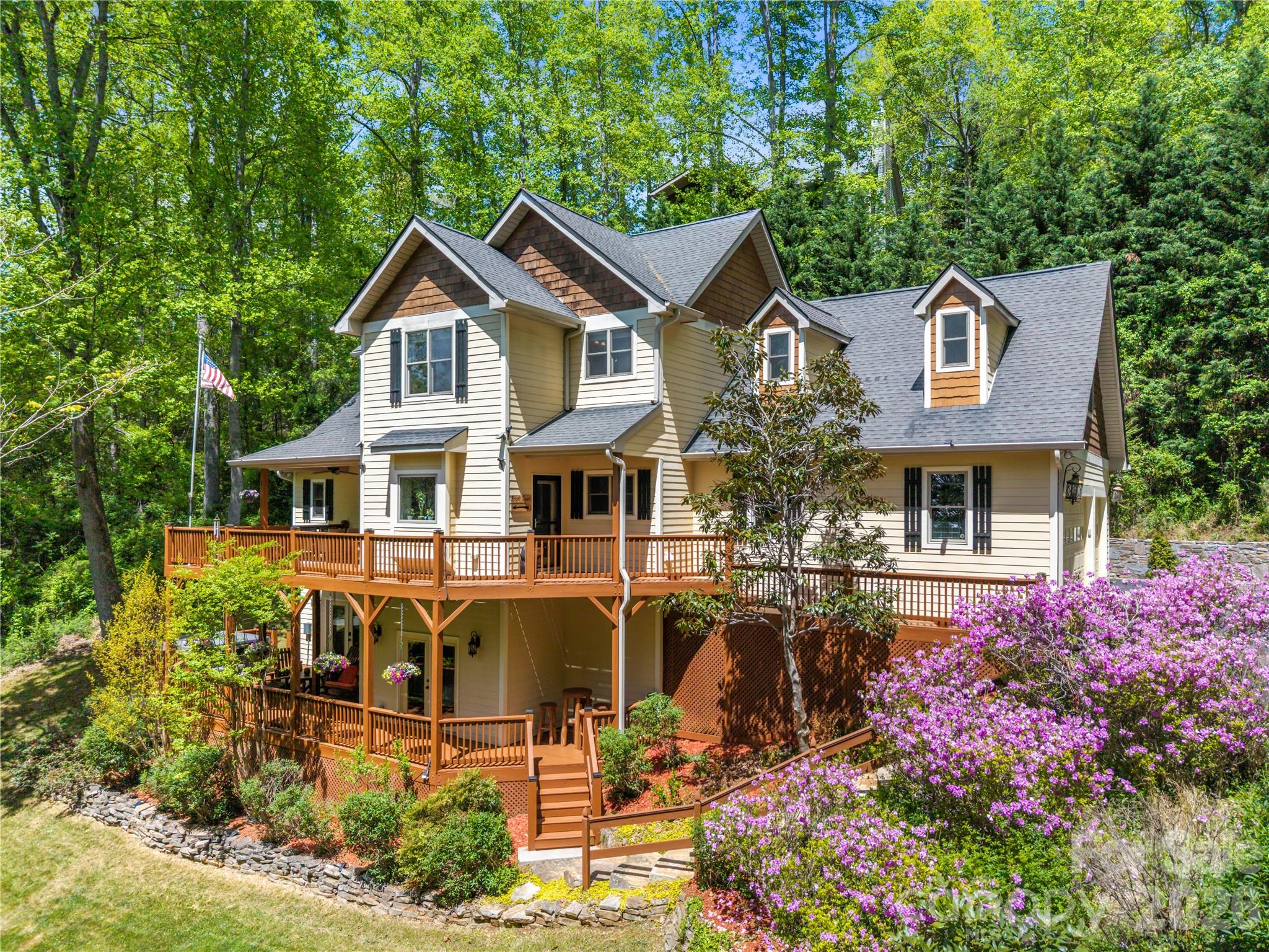 Welcome to 128 Churchill Downs, an exceptional move-in ready residence in the highly sought-after gated community of Fairview Downs. This beautifully maintained 3-bedroom, 3.5-bath home embodies refined mountain living with resurfaced hardwood floors, custom finishes, and a sophisticated modern farmhouse aesthetic throughout. Thoughtfully designed for both everyday comfort and effortless entertaining, the home features a main-level primary suite, a bright four-season sunroom, and expansive living spaces filled with natural light.
Offering remarkable flexibility, the two bedroom upper level includes a spacious bonus area ideal for a home office, music room, art studio, or media lounge. The lower level features two additional bonus rooms perfect for guest accommodations, a fitness space, hobby rooms, or additional storage. Also on the lower level is a wired media and family room, along with private guest quarters and a separate entrance—ideal for visitors, multigenerational living, or continued Airbnb income potential.  Outdoor living is equally impressive, showcasing a spectacular two-level wraparound deck, beautifully tiered gardens, a fire pit, and a private hot tub retreat perfectly positioned to enjoy the peaceful surroundings and mountain air. Additional highlights include a spacious triple garage and abundant storage throughout. Residents of Fairview Downs enjoy access to community amenities including a walking path, a creekside park, picnic pavilion, playground, and serene green spaces.  Conveniently located just minutes from shopping, dining, the Biltmore Estate, and downtown Asheville, this rare turnkey property offers an exceptional blend of luxury, privacy, and convenience in one of Western North Carolina’s most desirable communities