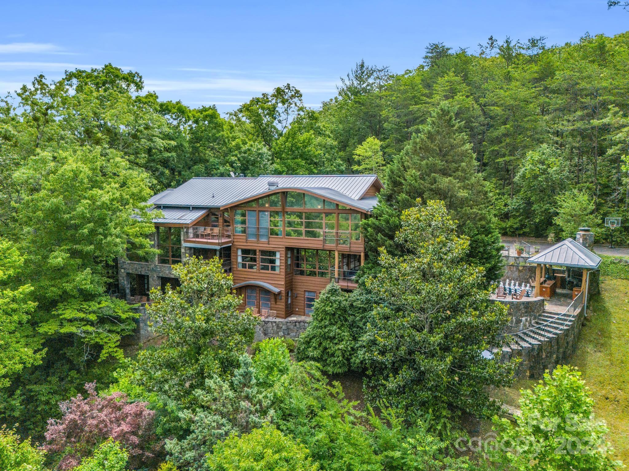 Overlooking Lake Lure and Rumbling Bald, this former boutique hotel and contemporary work of art offers breathtaking lake & mountain views from nearly every room. Stone patios w/ covered cook-center, gas grill, wood burning grill, sink, concrete countertops and hot tub.  Each bedroom has a private full bath as well as access to a private stone patio or deck.  The gourmet professional kitchen has 2 Sub-Zero refrigerator/freezers, a professional Viking 6-burner w/ grill cooktop with stainless hood, quartz countertops, center island with prep sink, lots of pantry space & half bath located just off the kitchen.  The dining room provides views from the bank of glass windows & doors w/ease of access to the outdoor patio & kitchen. The great room w/25' ceilings, walls of glass windows &  fireplace provide a lovely gathering area for multiple uses. Over 8 ½ acres includes a masterfully designed boat house w/ stone seawall, deck, dock, & gazebo. See attached for full descrip & photos.