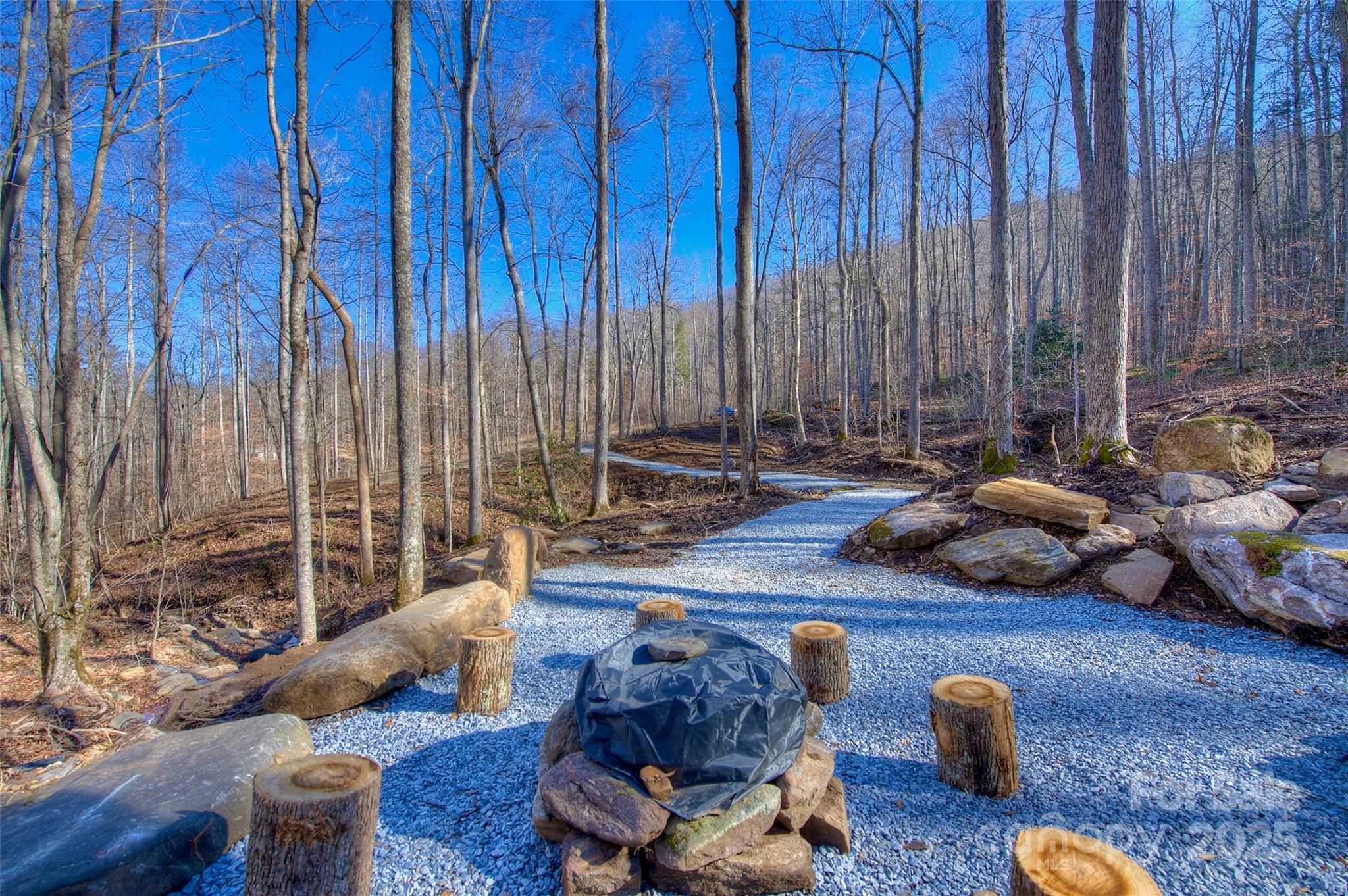 CLEAN | PURE | MOUNTAIN LIVING

Prime 4.2-Acre Mountain Retreat – Shadowood, Spruce Pine, NC

Discover your dream mountain home site on this stunning 4.204-acre parcel in the desirable Shadowood Community, just off US Hwy 19-E near Spruce Pine, NC. Priced at $189,180, this private lot offers mature hardwood forest, rolling terrain, & breathtaking long-range mountain views—perfect for raising a family or enjoying retirement in a park-like setting.

Enter via a newly installed bluestone driveway flanked by two boulders—ideal spot for your family gate, creating your own secluded mountain enclave. Crystal-clear headwaters of Brushy Creek originate on the property, winding through with soothing sounds & natural beauty at your doorstep.

Key Features – Exceptional Value

*Brand-new 3-bedroom septic system installed & ready
*Electric available at neighboring property (low hookup cost)
*Pure mountain spring water piped & ready to tap—some of the cleanest in North America
*Thoughtfully designed fire pit area w/ stone seating & accents for stargazing evenings
*Professional site prep: multiple level building sites cleared, graveled drives & pathways in place, minimal grading needed
*Scenic gravel paths & stone steps blend into the landscape, leading to peaceful creek views

Shadowood is a mature ~130-acre community with diverse homes—from modest to high-end—set in an almost National Park-like atmosphere. Well-maintained, easy-grade roads (built & cared for by a top Western NC road builder) connect the neighborhood. Enjoy Appalachia's rich ecosystem, abundant wildlife, & protected mountain views.

This turn-key ready lot has the hard work done: choose your home placement among gentle slopes & wooded vistas. Build a cozy cabin, modern escape, or full-time residence amid serenity & natural splendor.

Low-restriction community with easy access to amenities: minutes to Spruce Pine (downtown, Penland School of Crafts, Grassy Creek Golf & Country Club, hospital, new  state-of-the-art fitness facility w/ indoor pool). 10 min to Blue Ridge Parkway adventures; 15 min to Burnsville; 30 min to Grandfather Mountain, Linville Falls, Lake James, Marion & I-40; 50 min to Asheville; 60 min to Johnson City, TN & Tri-Cities Airport; 2 hrs to Charlotte.

Every drive to the post office or grocery becomes a scenic journey most people only dream of. Leave the "downcountry" stress behind—let the altitude improve your attitude.

This isn't just land—it's your private slice of Blue Ridge paradise. Mountain living starts here.

Contact today for a private tour & claim this mountain gem!