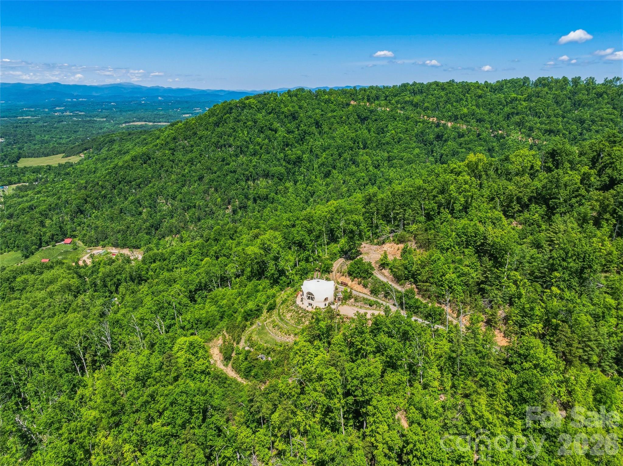 Welcome to Azura Gardens. A rare Mountain Sanctuary with a Dome Home & Guest Cottages.

Perched above the clouds, this 28 acre open-use zoning mountain estate offers a rare blend of breathtaking panoramic views, timeless design, and exceptional privacy- while being 10 minutes from Weaverville and 17 minutes from downtown Asheville. An ideal setting for a wellness retreat or intentional gathering space. Two existing modern cabins provide consistent rental income. Build on what is already established or create something entirely new - the options are endless at Azura Gardens!

  At the heart of the estate stands a remarkable ~3,400sf Dome Home, a handcrafted monolithic structure designed with energy efficiency and artistry in mind. With two bedrooms, two and a half baths, and both a full kitchen and kitchenette, the home balances comfort with sustainability. Interior features include custom woodwork, arched details, and a built-in observation beehive. Spa-like bathrooms showcase custom tubs and a steam shower, while a wood stove in the living room provides cozy off-grid heating. Exceptional insulation with an R-value of 84 ensures year-round comfort. Every detail of this unique residence reflects vision, intention, and craftsmanship.

  Complementing the main house are two income-producing exquisite guest cottages, each designed as a retreat of their own. The Stone House (approx. 295 sq. ft.) shows elegance with a Moroccan aesthetic, featuring stucco walls, stone cabinetry, artisan finishes, and an open-plan layout with a walk-in shower. The Creek House (approx. 295 sq. ft.) offers serene living at the water’s edge, inspired by Japanese Wabi-Sabi design. With stucco interiors, stone cabinetry, a walk-in shower, and a patio overlooking the spring-fed creek, it is a peaceful hideaway connected to nature by a winding stone path.

  The roughly 28 acres of land surrounding the residences is equally extraordinary. A year-round creek meanders through the property, while private wells and multiple natural springs provide pure, abundant water. The grounds are alive with beauty and self-sufficiency: vibrant pollinator gardens and an apiary support bees and butterflies, a rose garden adds cultivated charm, and fruit trees are scattered throughout the landscape. With ample space for additional building sites, the property offers flexibility for expansion while preserving its sense of seclusion. Trails and roadbeds wind across the terrain, inviting exploration by foot, bike, or horseback, and providing endless opportunities for outdoor adventure.

  Each element of this sanctuary has been created with care and intention, resulting in a property that is both functional and inspirational. Whether you are looking for a private mountain retreat, a sustainable homestead, or a profitable venue for hosting and gathering, it offers a rare opportunity to own such a unique piece of property- ready for its next owner to continue to add and make it their own.

  Interactive map link: https://id.land/maps/9960b013da816c6381914f40593e84e7/share/unbranded
