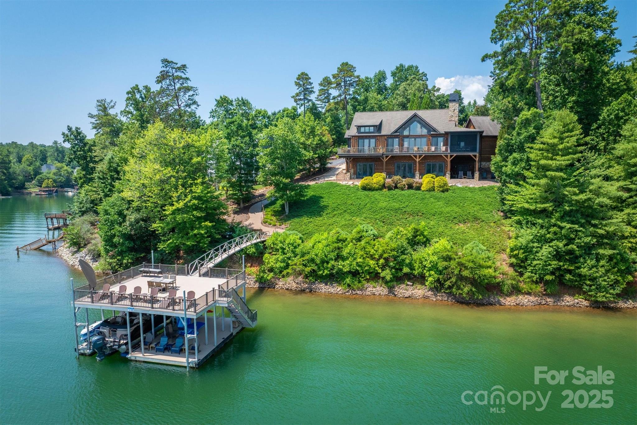 Experience luxurious lakefront living in this stunning custom home featuring breathtaking long-range waterfront views. Nestled on a serene shoreline, this residence showcases a dramatic cathedral ceiling and a spacious great room centered around a cozy gas fireplace. Main floor hosts the primary suite with a spa-like bath and  spaciouswalk in closet.  Entertain in the gourmet kitchen, equipped w/high-end appliances, large island & hidden walk-in pantry. Enjoy year round outdoor living on the screened porch with a wood-burning fireplace. Guests will love two additional bedrooms in the lower level, each with ensuite bath, one with private sauna. The lower level also boasts a wine cellar, wet bar, and easy access to the floating covered aluminum dock. A scenic fire pit area invites evening gatherings by the water. Crafted with rich poplar bark & cedar siding complemented by a 2-car attached garage, this home is the perfect blend of rustic elegance & modern convenience.  Offered turnkey!