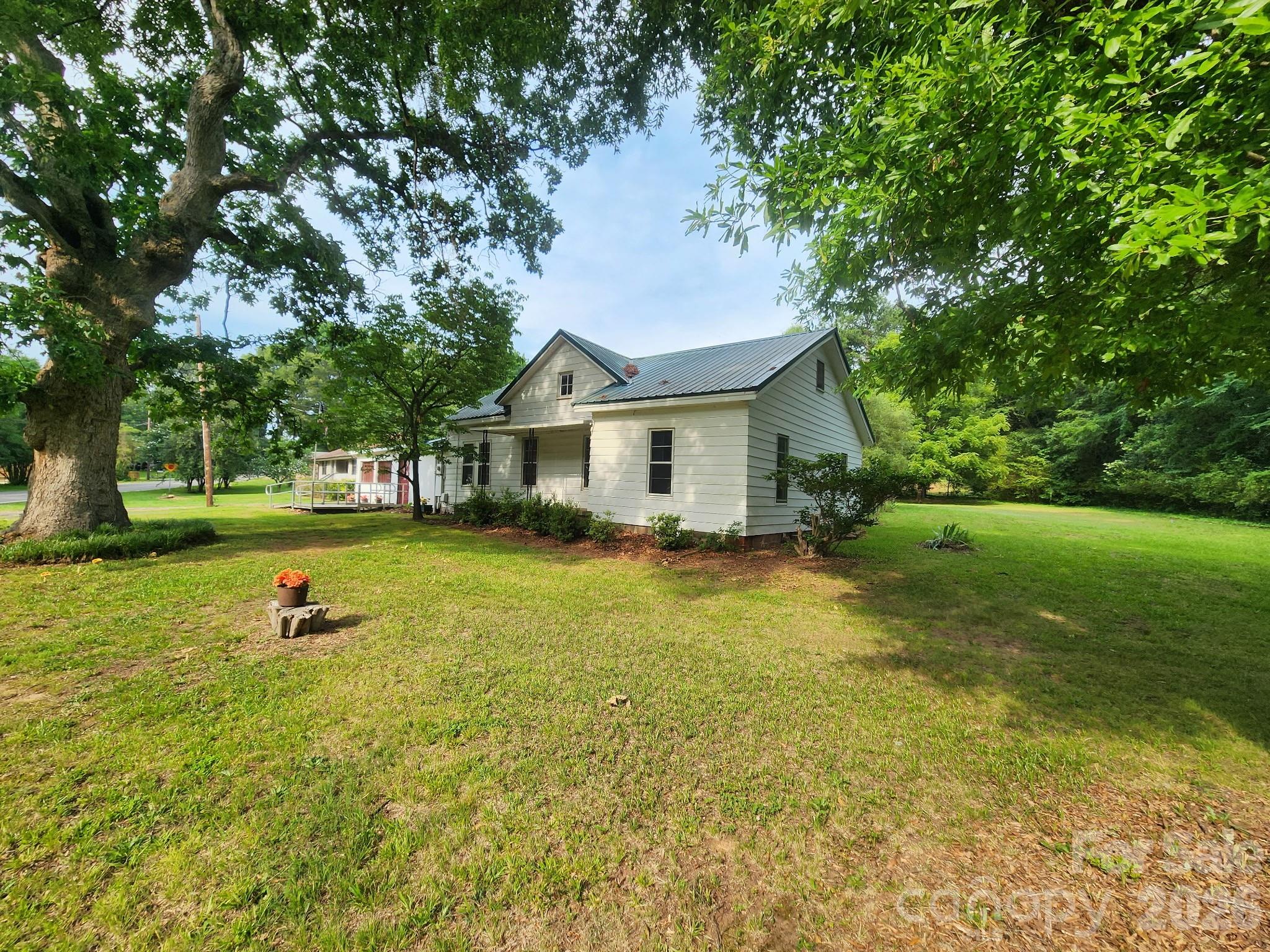 Great Location and a Home that's ready for your vision. Metal Roof in 2012, Natural Gas Heat Unit 2015. An Attached Metal Carport was made into a living space. This room has baseboard heat and a wall unit A/C - No Permits were pulled for this carport living space. The total heated sq. ft. of 1478 includes the Living Space in the carport, which has approximately 330 sq ft. Railroad tracks are beside the property; there is an easement. Active Train per the seller; it goes by a few times a day and does blow horn. Piedmont Natural Gas Easement runs alongside and in the same direction as the railroad easement- side by side. This was an old homeplace, and the home could be renovated, but the seller will make no repairs, and the home is being sold in its as-is current condition with no representation as to the condition of the home.  This could be a great building lot if an investor wanted to tear down the home and build new. It's a Nice level lot with several trees. Zoned N1-A. Older greenhouse/ out building on the property. No permits on file, no current survey. There is an old Plat from 1914 in the attachments. Fireplace/Chimney is non-functioning; it has been covered up inside the home and is not visible from the roof; the brick Chimney can be seen in the attic. The front room (living room) at the front entry porch was used as a bedroom; this room has no framed closet.