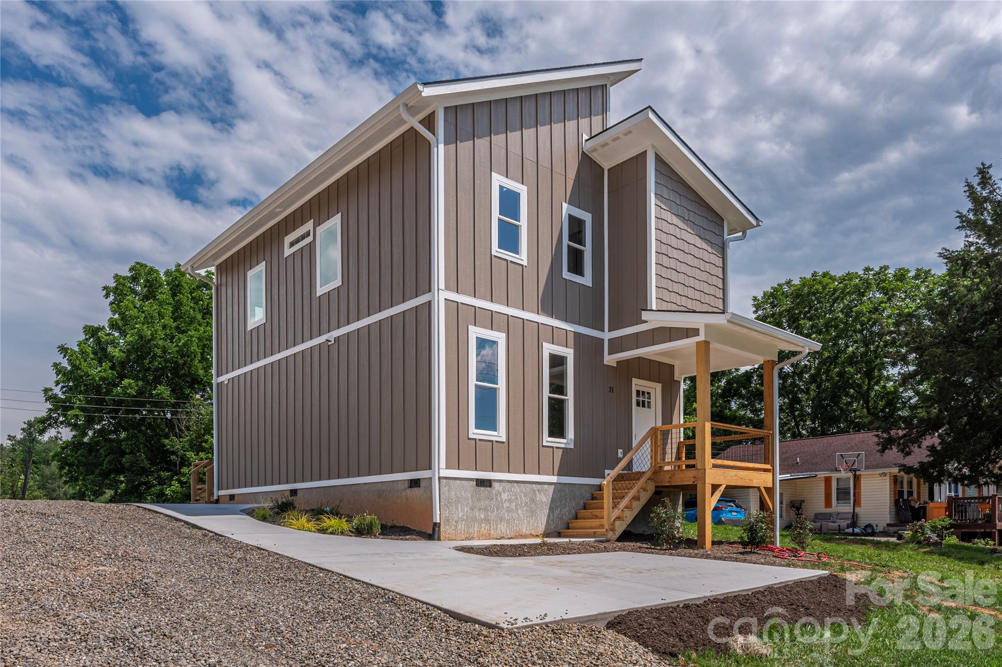 Move in ready!  Start fresh and be the first to make this new construction your home! Modern design meets comfortable living in this striking two-story home featuring a distinctive roofline and thoughtful architectural details throughout. The main level welcomes you with a spacious open floor plan designed for both everyday living and entertaining. Natural light fills the living area and flows seamlessly into the beautifully appointed kitchen. The kitchen is truly the heart of the home, highlighted by stunning and unique quartz countertops and an oversized island with generous bar seating, perfect for casual meals or gathering with friends and family. With direct access to the back deck, the space is ideally suited for hosting and enjoying indoor-outdoor living.

Upstairs, the bedrooms feel exceptionally spacious thanks to soaring cathedral ceilings that add character, openness, and an airy atmosphere throughout. The primary suite offers a comfortable retreat and features a custom barn door for added style and charm. Thoughtfully designed with contemporary finishes and functional comfort in mind, this home creates a welcoming living experience just minutes from downtown Asheville.

Additional features include a large storage area located beneath the stairs, providing excellent space for organization and extra belongings. The front exterior photo reflects the existing gravel driveway. A paved driveway will be completed prior to closing offering plenty of parking for you and your guests.  Concrete sidewalks are in place.