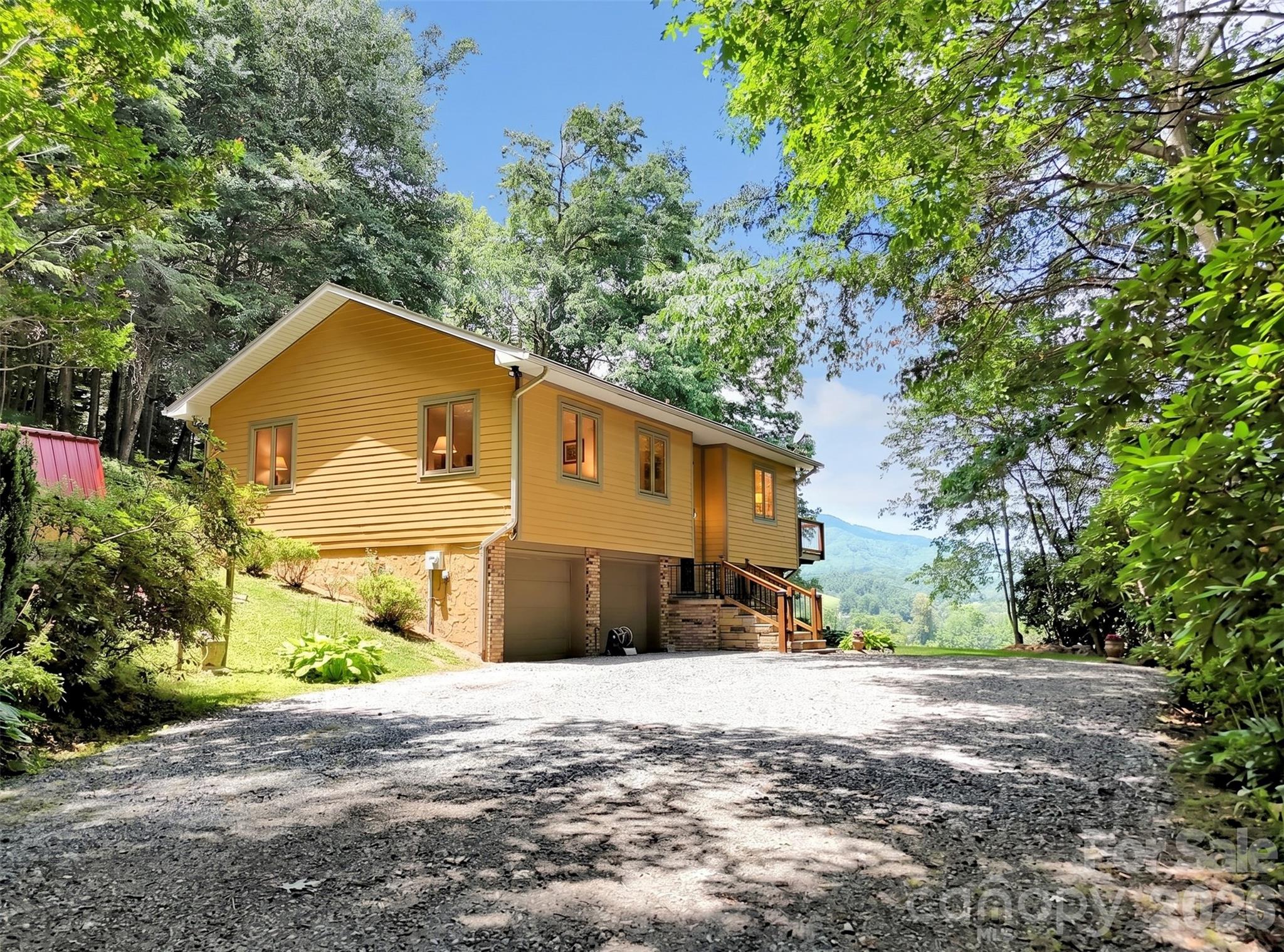 Experience mountain serenity in this beautifully maintained 3 bedroom, 2 bath home offering year round, long range views of the Smoky Mountains. This peaceful retreat is ideal for nature lovers seeking both privacy and convenience, with a long list of thoughtful updates that make it truly move in ready.  Recent improvements include a 2020 Rheem high efficiency heat pump, 2020 Buck Stove ventless gas log fireplace, 2022 50 gallon Rheem water heater, 2022 Sherwin Williams exterior paint, 2023 - Installed (2) Marvin windows in the main living area on the north side, 2024 deck boards and rails, 2025 septic pumped, 2026 stone front steps with new posts/rails, plus updated lighting and ceiling fans throughout and leaf gutters and French drains.  The kitchen features granite countertops and stainless steel appliances, while the lower level offers excellent potential as a second living area with a convenient half bath. Storage is abundant with a two car garage and two outdoor storage buildings.  Nature lovers will enjoy a spacious deck great for entertaining and ideal for gatherings overlooking the spectacular long range view of the smoky mountains, a covered outdoor section is perfect for sunny afternoons or peaceful rainy day unwinding, five Ring motion lights/cameras let you observe visiting wildlife, and 20 mature blueberry bushes are a rare find that will delight gardeners, homesteaders, and anyone who loves fresh, homegrown fruit.  Ideally positioned just minutes from the vibrant dining and boutique shopping of Waynesville and Maggie Valley, this inviting home blends mountain tranquility with everyday convenience. Quick access to I 40 makes commuting to Knoxville or Asheville effortless, while still allowing you to retreat to a peaceful, private setting at the end of the day. A wonderful opportunity for anyone seeking comfort, accessibility, and the best of Western North Carolina living.