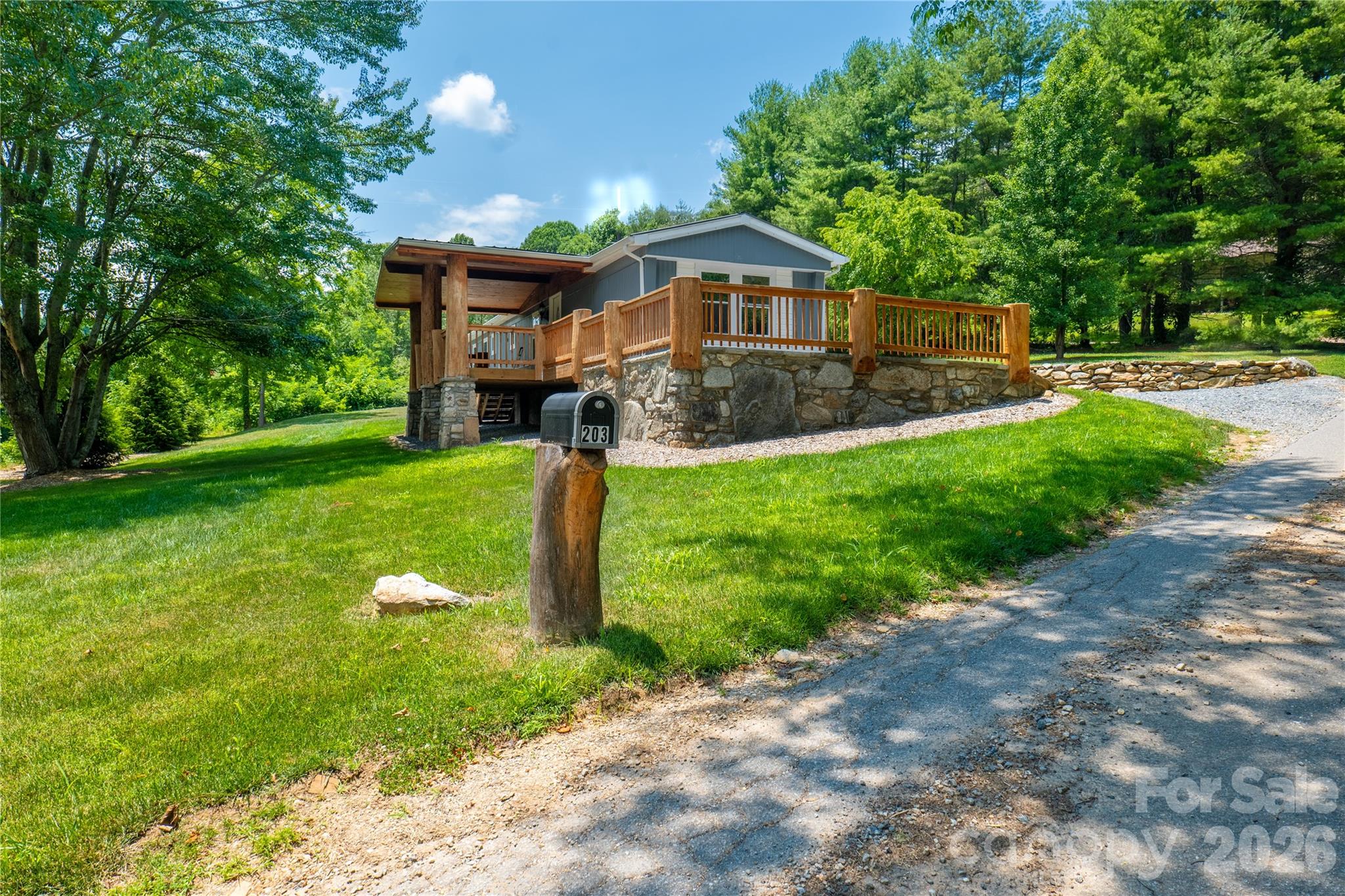 Move-in ready home, this charming Clyde home blends modern comfort with timeless mountain character. Nestled on approximately 0.70 acres, the property features a permanent foundation, an open floor plan, beautiful wood accents, abundant natural light, and a tastefully updated kitchen complete with stainless steel appliances. The home features  an expansive covered deck, beautifully accented by handcrafted columns made from locally sourced Clyde locust trees. Ennjoy the peaceful setting surrounded by mature landscaping and custom stone retaining walls. Conveniently located at 203 Justice Drive, you're just minutes from downtown Clyde, downtown Waynesville, and I-40, offering easy access to shopping, dining, outdoor recreation, and commuting while still enjoying the privacy and serenity of mountain living. This thoughtfully updated property is the perfect place to call home.