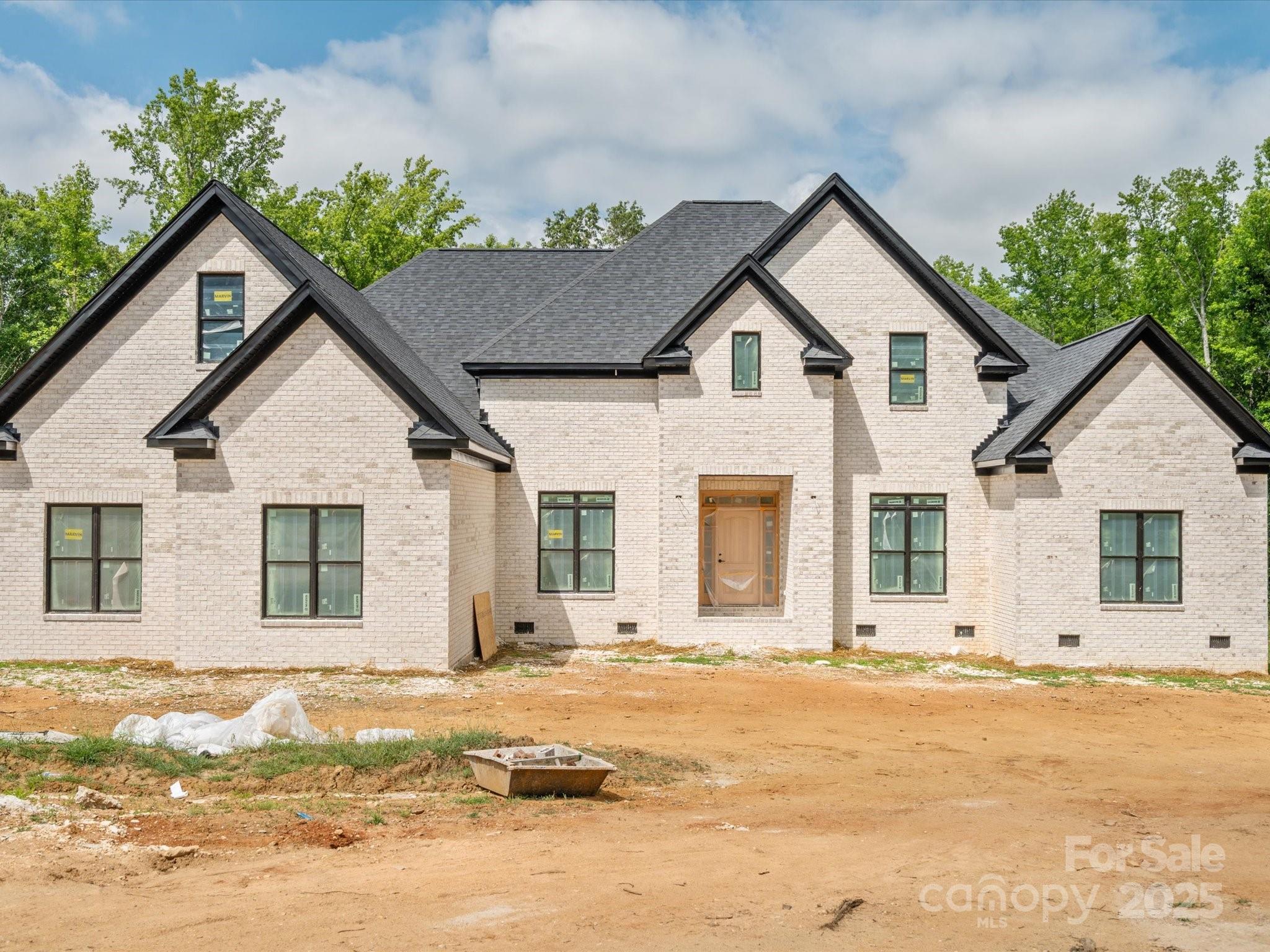 Discover luxury country living on 5 private acres in this stunning newly completed custom home offering over 5,300 heated square feet of thoughtfully designed living space. Originally offered during construction with buyer finish options, this home is now finished and showcases exceptional craftsmanship and high end designer selections throughout. Beautiful stone accents, custom tile work, quartz countertops, oversized luxury plank flooring, craftsman style trim, and soaring 10-foot ceilings create an impressive blend of elegance and comfort.
The spacious main level primary suite features an enormous spa inspired walk in shower, generous walk in closet with room for a center island, and plumbing and electrical already in place for a second laundry area. The gourmet kitchen is designed for entertaining with an oversized island, prep sink, and dedicated coffee bar. A second main level bedroom with private ensuite bath offers an ideal setup for guests or multigenerational living.
The home is currently permitted as a 3 bedroom residence with 4.5 baths and includes two additional unfinished flex spaces already equipped with HVAC, plumbing, and venting, offering potential for expanded bedroom, office, fitness, hobby, or media space. An additional upper level flex area provides even more versatility for a second office, bonus room, or recreation area. Buyers seeking additional bedrooms may explore an engineered septic expansion. Enjoy peaceful views from the covered rear patio accessible from both the great room and primary suite. Additional features include handicap accessible doorways, 400 amp electrical service, two 50 gallon water heaters, approximately 2 acres already cleared, and a 3 car garage with 10 foot ceilings plus a 220 volt outlet in the workshop area.
Appliances and decorative light fixtures have intentionally been left for the new owner to personalize. The recent price adjustment reflects this opportunity, and buyers may be able to incorporate appliance selections into their financing, subject to lender approval.
New concrete will be poured the last week in May.  Photos will be updated June 6. Appraisal completed and home is priced significantly below appraised value.  Cameras on site.  Please wear shoe covers that are provided when touring with agent.
A rare combination of privacy, quality construction, flexibility, and luxury finishes just waiting for its first owner.