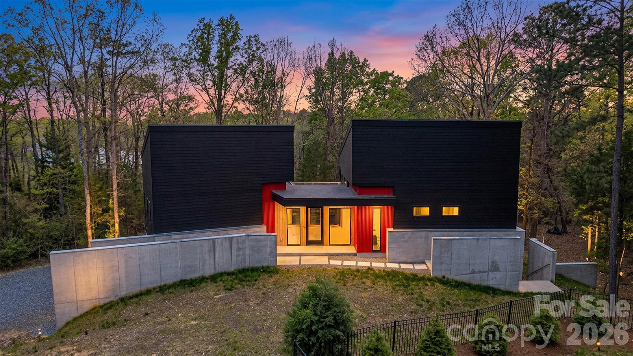 Set within the serene, tree-lined enclave of Heron Cove near the shoreline of Lake Wylie, this architecturally striking 2024 residence redefines modern lakeside living. Thoughtfully sited on a private, and wooded 0.81-acre lot with seasonal lake views, the home masterfully blends contemporary design, effortless flow, and refined privacy. Just minutes from Lake Wylie’s boating, trails, and recreation, along with an easy 40-minute drive to Charlotte.

Natural light pours into every space through expansive, strategically placed windows and glass walls that frame the surrounding landscape like living art, creating an atmosphere that feels simultaneously monumental and deeply grounded. The open-concept layout unfolds with quiet sophistication, guiding you seamlessly from one area to the next while preserving intimate pockets of privacy. The chef’s kitchen commands attention with its dramatic custom concrete island in a striking teal finish, premium Wolf appliances, dual dishwashers, integrated appliance garages, dedicated beverage center, and a built-in barista station turning the space into a true centerpiece for gathering and entertaining. An elevated central courtyard terraces blur the boundaries between inside and out, offering a dramatic perch for al fresco dining, morning coffee with lake breezes, or peaceful evenings under the stars.

Built with forward-thinking precision, the home features energy-efficient systems, solar-ready design, smart-home pre-wiring, two tankless water heater, and sustainable construction details throughout. Concrete and tile flooring, attached two car garage, and a no-HOA setting further enhance its low-maintenance appeal. This is more than a home—it’s a rare opportunity to own a thoughtfully crafted modern retreat in one of Lake Wylie’s most desirable pockets, where privacy, views, and refined living converge. Schedule your private showing today and experience firsthand the exceptional design, setting, and elevated lifestyle that set this property apart.