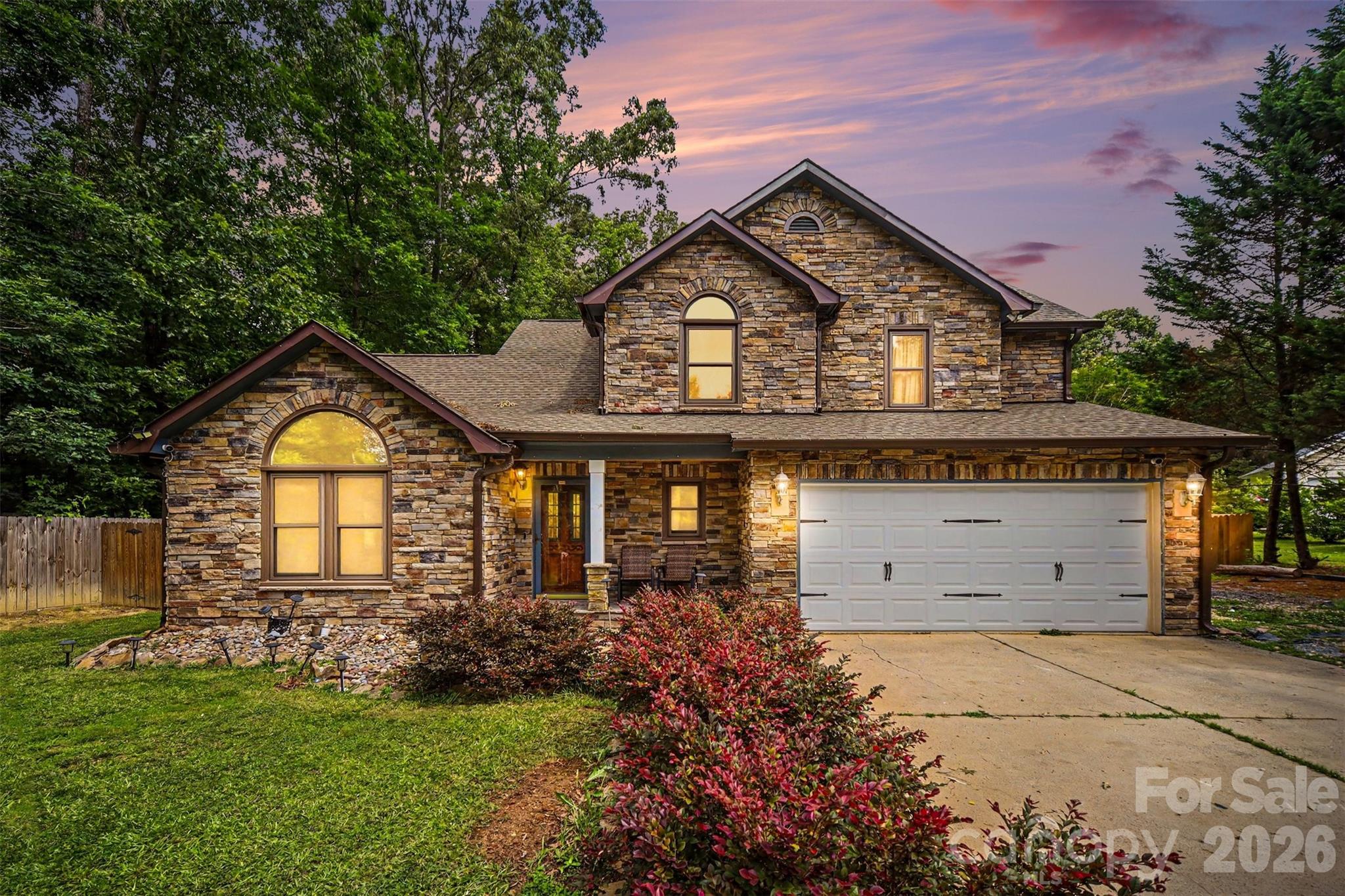 Nestled on approximately half an acre, this beautifully maintained full-stone home welcomes you with an extra-long driveway, a charming front porch, timeless curb appeal, and plenty of space to enjoy both inside and out. Step inside to an inviting great room featuring soaring vaulted ceilings and an exposed wood beam that adds warmth and character.

The main level offers a functional and flowing layout, including a dining area, kitchen, breakfast nook, and a cozy living room complete with a wood-burning fireplace. Large sliding glass doors fill the space with natural light and provide seamless access to the backyard. Rich wood doors and molding throughout the home add timeless appeal, while durable LVP flooring extends through the main living areas and bedrooms.

Upstairs, the spacious primary suite features a vaulted ceiling, a private en-suite bathroom with a soaking tub, separate shower, dual vanity, and a walk-in closet. Two additional bedrooms share a full bathroom with tile finishes and an extended vanity offering ample counter space.

Enjoy outdoor living in the fenced backyard, complete with a stone patio and a wooded tree line that enhances privacy and creates a peaceful setting.

Conveniently located near Highway 485, shopping, dining, and everyday amenities, this home is also just 10 minutes from Matthews and all that its charming downtown district has to offer. This property combines space, character, and location—making it a wonderful place to call home.