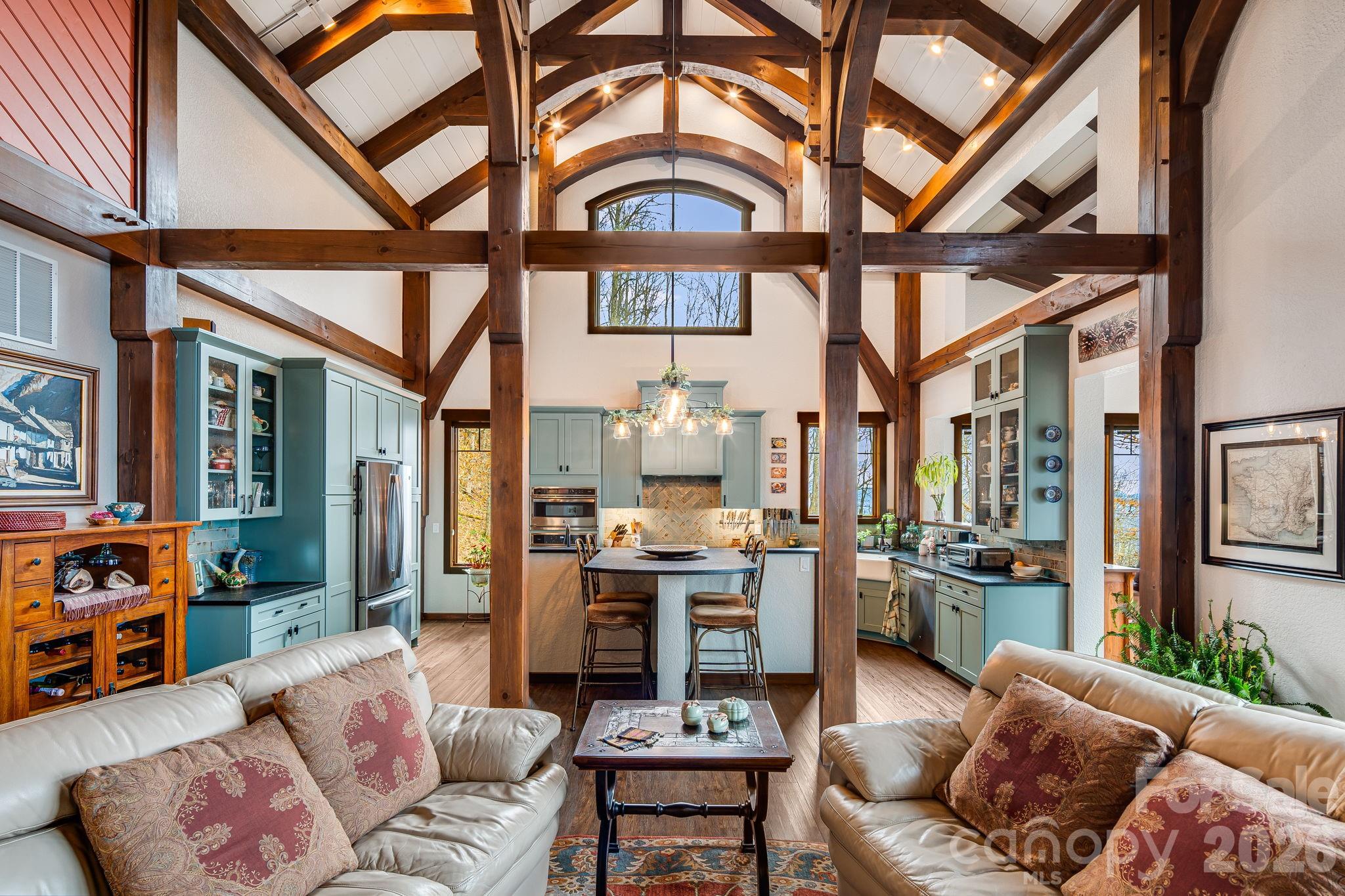 Perched at a rare 4,000-foot elevation and bordering 39,000 acres of Nantahala National Forest, 2223 Scarlet Ridge is a masterfully crafted mountaintop estate where architecture, engineering, and nature exist in perfect harmony. Designed to capture sweeping long-range views while remaining naturally protected from extreme weather, the home offers cooler summer temperatures, dramatic cloud inversions below, and exceptional privacy.
This handcrafted timber-frame residence showcases cathedral ceilings, exposed beams, and seamless indoor-outdoor living that reflects both refined craftsmanship and deep respect for the surrounding landscape. Built to endure, the home features superior construction including a reinforced concrete foundation, Structural Insulated Panel walls, fiber-cement siding, high-performance windows, and advanced systems designed specifically for high-elevation living. Modern comforts include a three-zone dual-fuel HVAC system with energy recovery ventilation, whole-house generator, instant hot water, pristine private well water, and a high-efficiency cast-iron wood-burning stove. Set on 17.72 private acres with trails, open meadow, and direct access to protected wilderness, the land offers unmatched connection to nature. From expansive terraces to forest paths and sweeping 40+ mile views, this is a mountain retreat as intelligent as it is breathtaking.This property is a must see to appreciate all it has to offer.