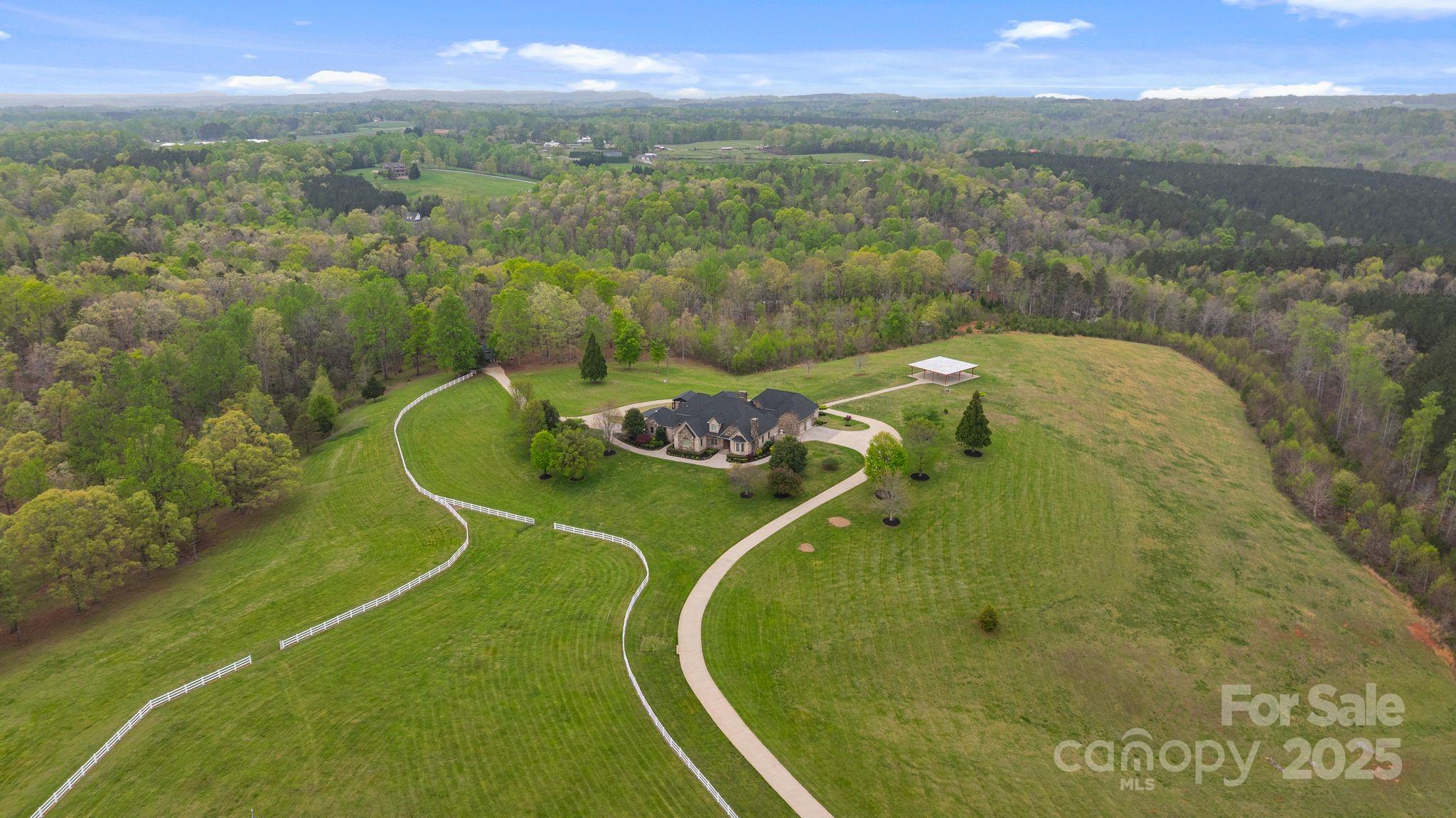 Nestled on 72+ acres of rolling pasture at the base of the Blue Ridge Mountains, this exceptional estate is a rare fusion of luxury, versatility, and breathtaking views. The primary residence offers 3,361 sqft of elegant living with three en-suite bedrooms, soaring 20 ft. ceilings, a gourmet kitchen, and a seamless connection to a private guest house via a charming breezeway. Designed for entertaining and lifestyle flexibility, the estate features a stunning pool, hot tub, 2 covered pavilions, and expansive terraces. Mulltiple guest cabins, and 16 bay vintage-style garage and motorcoach-ready storage building—convertible to equestrian use. A separate event center with ballroom, bar, prep kitchen and outdoor pavilion adds limitless possibilities. Above event center is another guest apartment/bridal suite. Whether you're a horse enthusiast, event host/entertainer, or car collector, this gated estate redefines private luxury living—just minutes from Tryon International Equestrian Center.