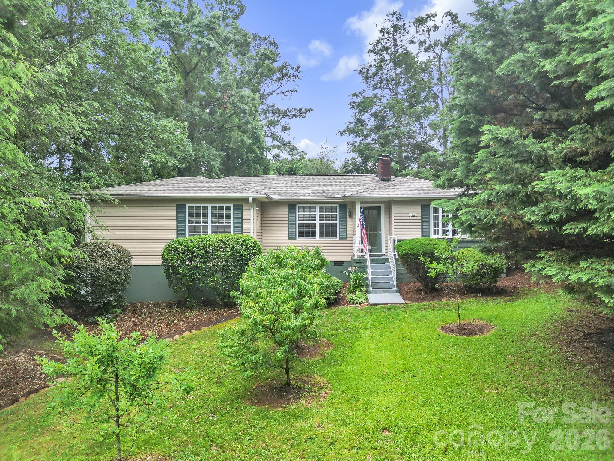 Location, charm, and flexibility come together beautifully at 103 Forest Avenue in Landrum. Situated on a spacious half acre corner lot within walking distance of downtown Landrum, this home blends timeless 1950s character with thoughtful modern updates. The roof was replaced in September 2021, and one of the HVAC systems was replaced in 2026, offering added peace of mind for the next owner.

Inside, you will find original hardwood floors, original doors, and crown molding that showcase the home's charm and craftsmanship. The living room is filled with natural light and features a gas log fireplace, creating a warm and inviting gathering space. Original French doors lead into the dining area and kitchen, where there is ample cabinet and countertop space, tile backsplash, and a full appliance package.

The main portion of the home offers two secondary bedrooms that share a spacious hall bath with beadboard accents, along with a primary suite featuring dual closets and an updated bathroom with dual sinks, a large shower, and abundant built in storage.

One of the most unique features of this property is the separate living wing located beyond the laundry area. With vaulted ceilings, a private entrance, access to the rear deck, a fourth bedroom, walk in closet, and full bathroom, this space offers endless possibilities. Whether you need an in law suite, second primary suite, private guest quarters, home office, workout room, playroom, or space for a home based business, this flexible area can easily adapt to your needs.

Outside, mature landscaping creates a beautiful setting with apple, peach, and pear trees, a Japanese maple, a circular driveway with additional parking, spacious deck, and an outbuilding with electricity. There is also plenty of room for gardening, outdoor entertaining, or simply enjoying the peaceful surroundings.

The home is wheelchair accessible and offers easy access in and out of the property. Located just off Highway 14, you are only minutes from downtown Landrum, Tryon, and popular destinations including Hendersonville, Lake Lure, Greenville, Spartanburg, and The Cliffs at Glassy.

Homes with this combination of character, space, flexibility, and location rarely come available. Best of all, there is no homeowners association.